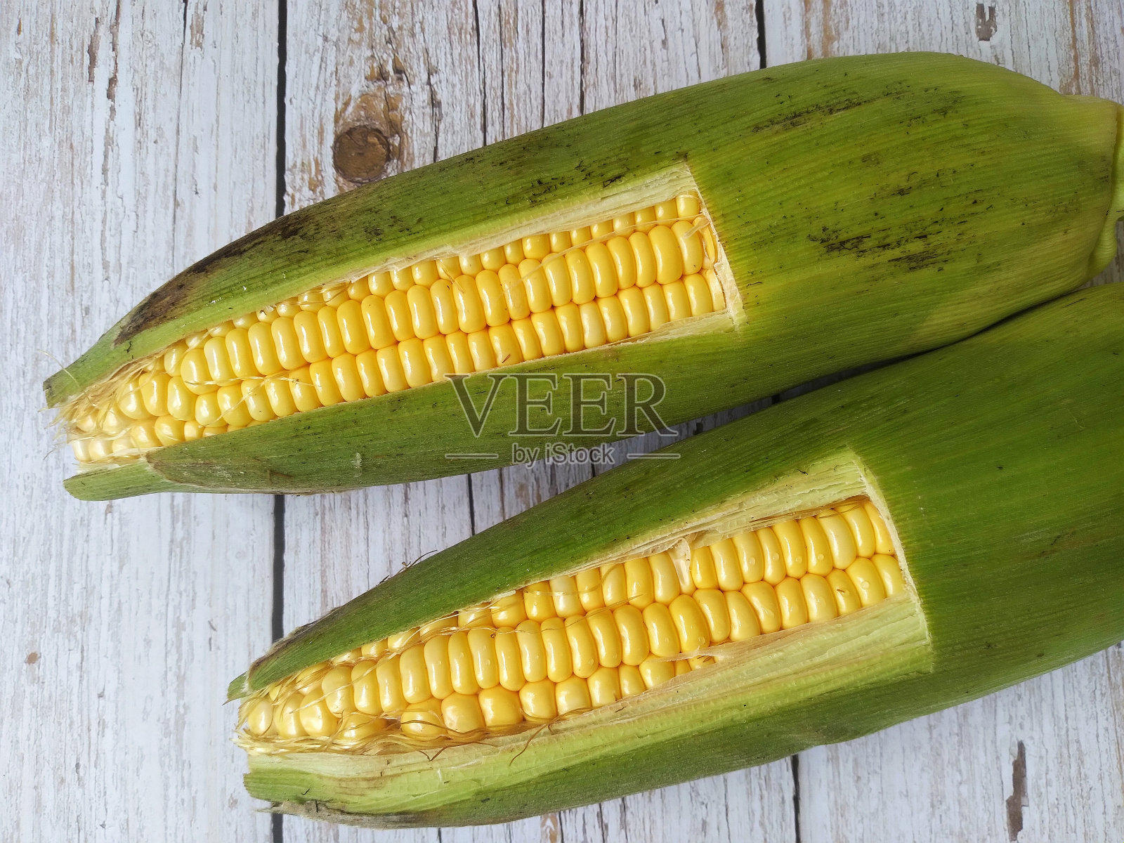 木制背景上的两颗甜玉米照片摄影图片