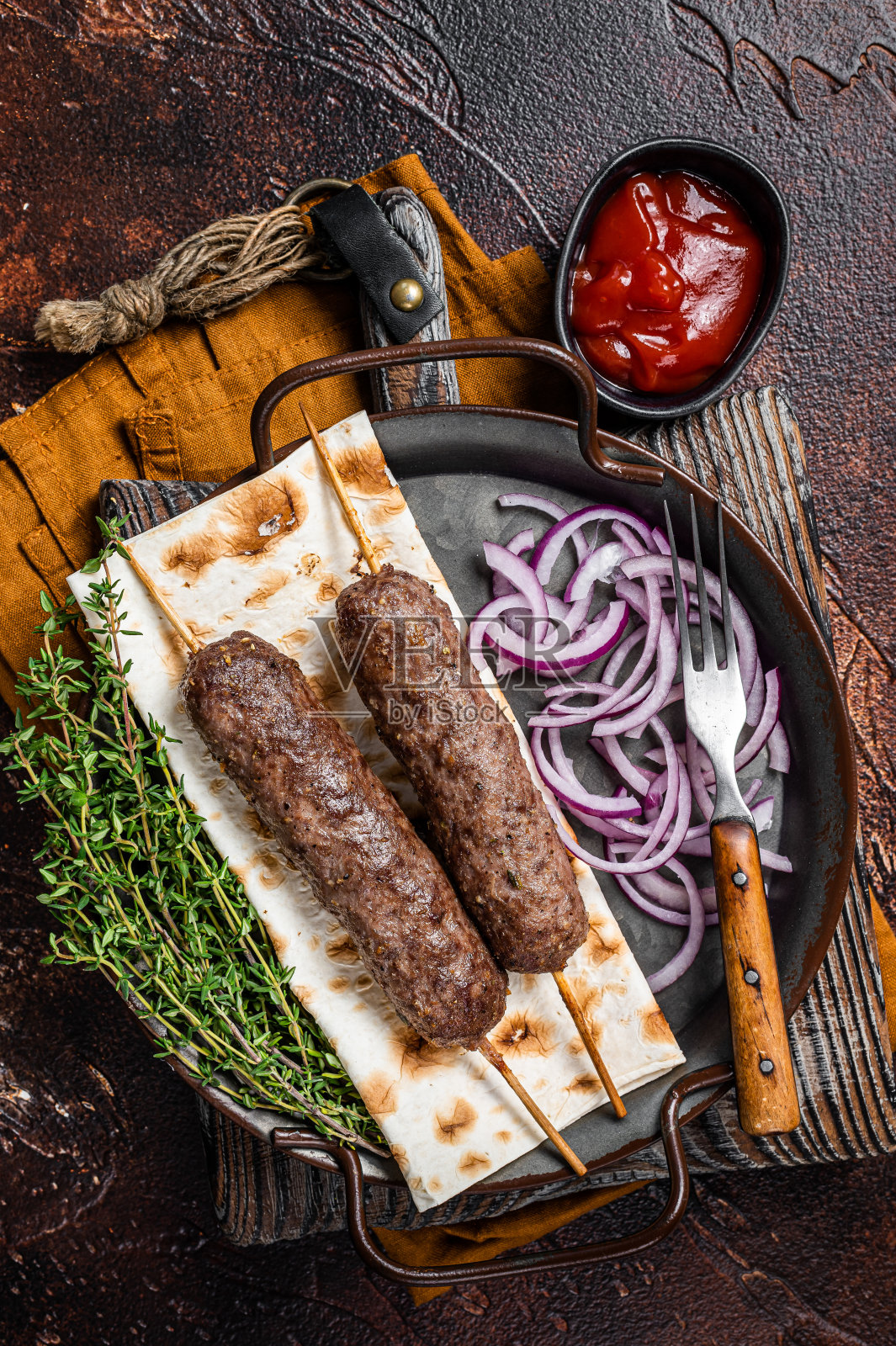 土耳其阿达纳烤肉串，羊肉牛肉末串在烤肉扦上，配薄饼和洋葱。深色背景。顶部视图照片摄影图片