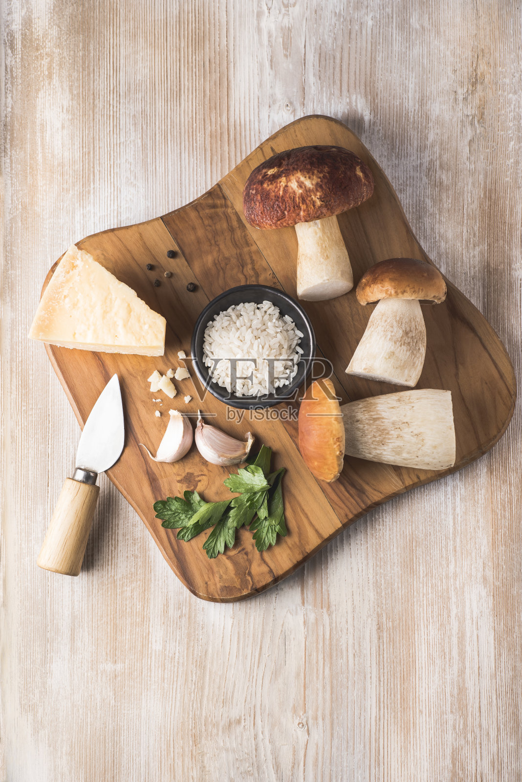 秋季或冬季野蘑菇牛肝菌(Boletus Edulis)在木制白色背景烩饭的配料。牛肝菌，米饭，欧芹，帕尔马干酪。健康的传统诺意大利食谱照片摄影图片