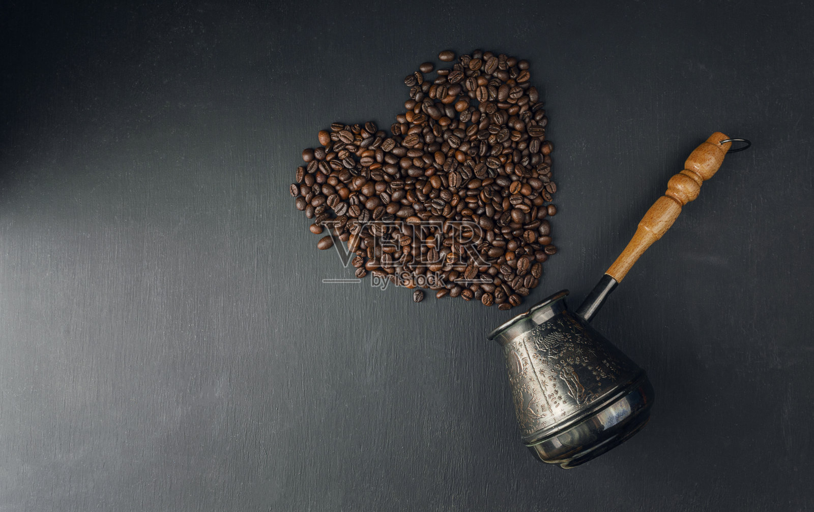 早晨咖啡。谷物散落在黑暗的桌子上。木制背景的咖啡杯，热而新鲜的早晨咖啡。照片摄影图片