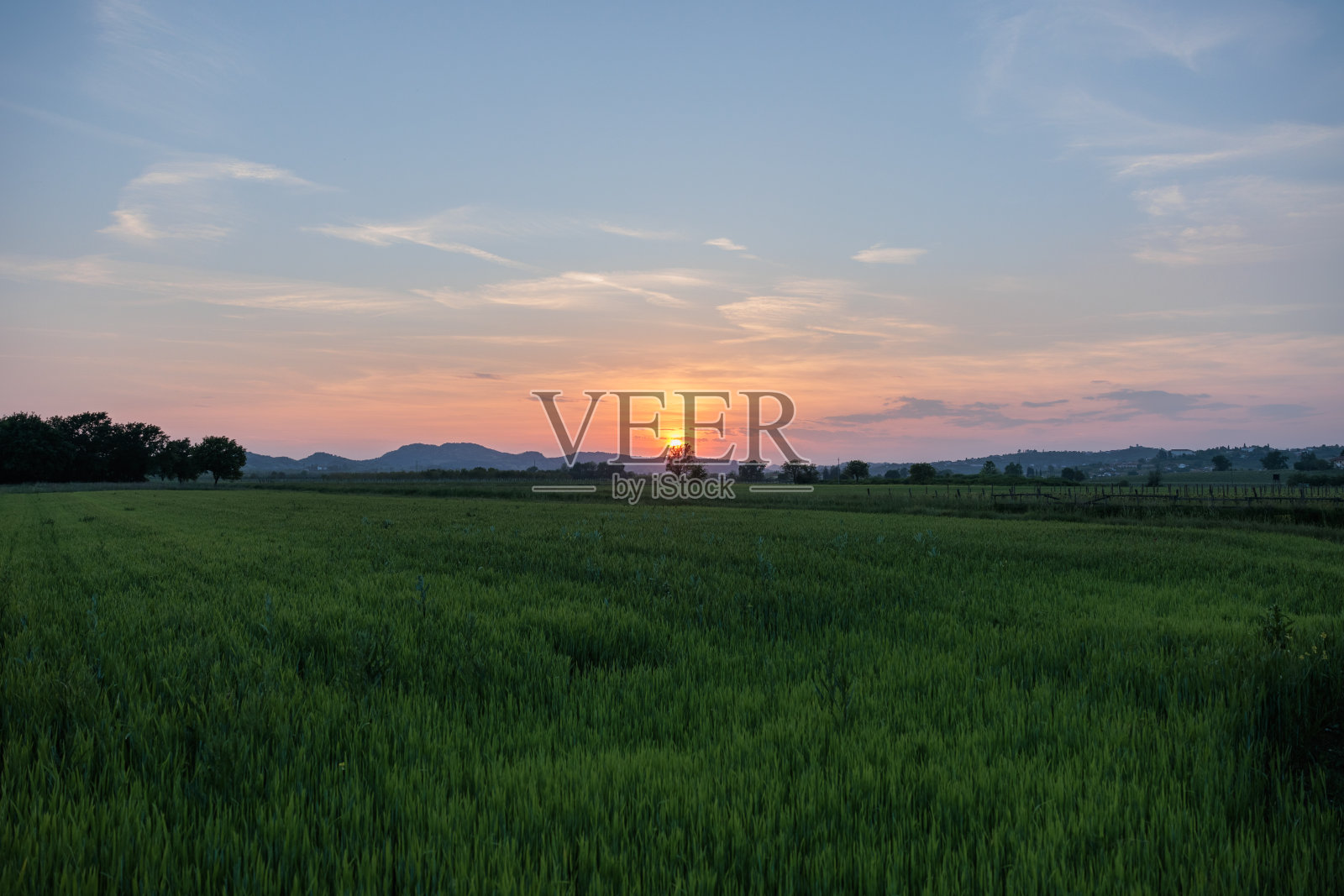 春天的日落在乡村，耕地，森林和远山下部分晴朗的天空照片摄影图片