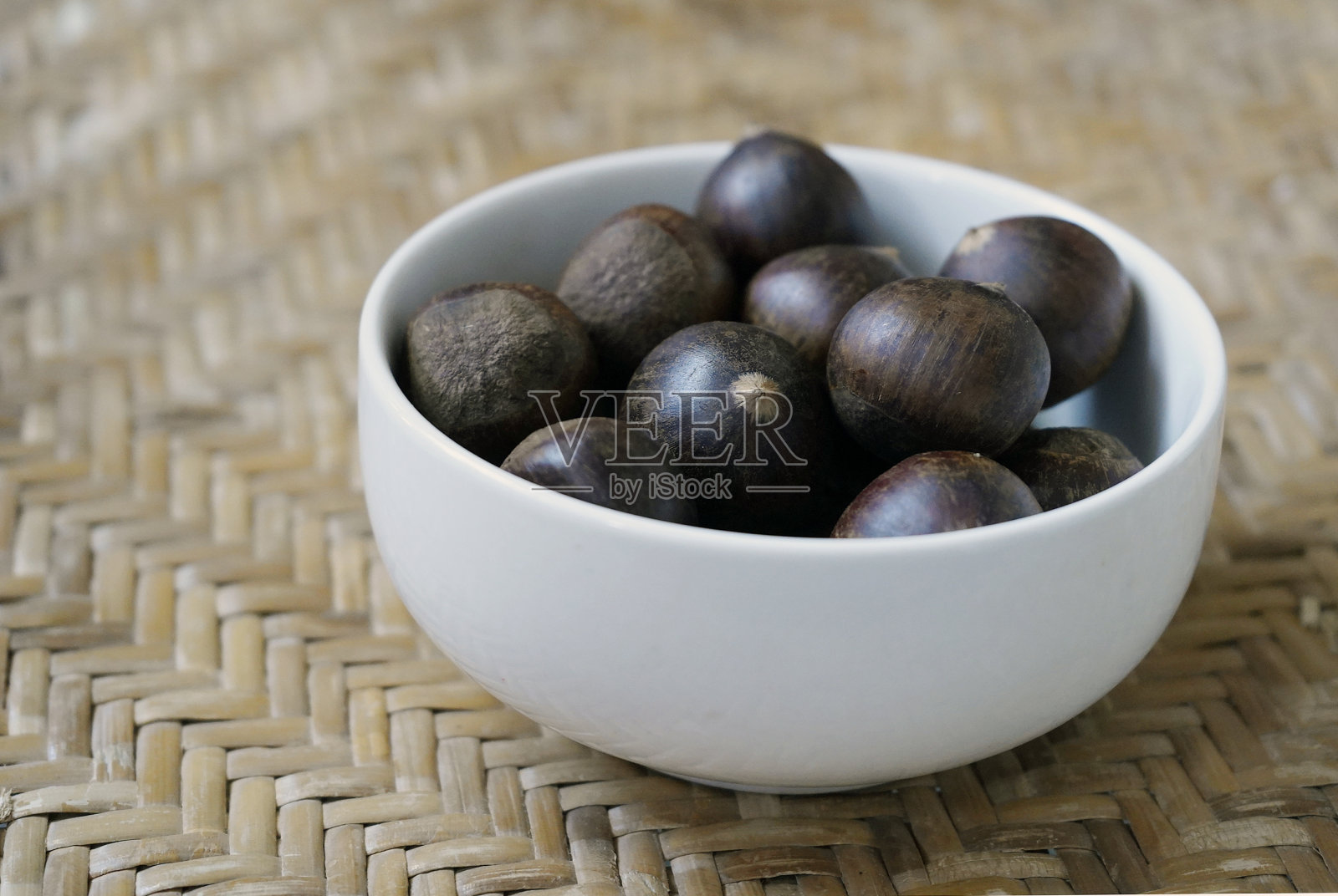 一碗板栗放在藤席上照片摄影图片