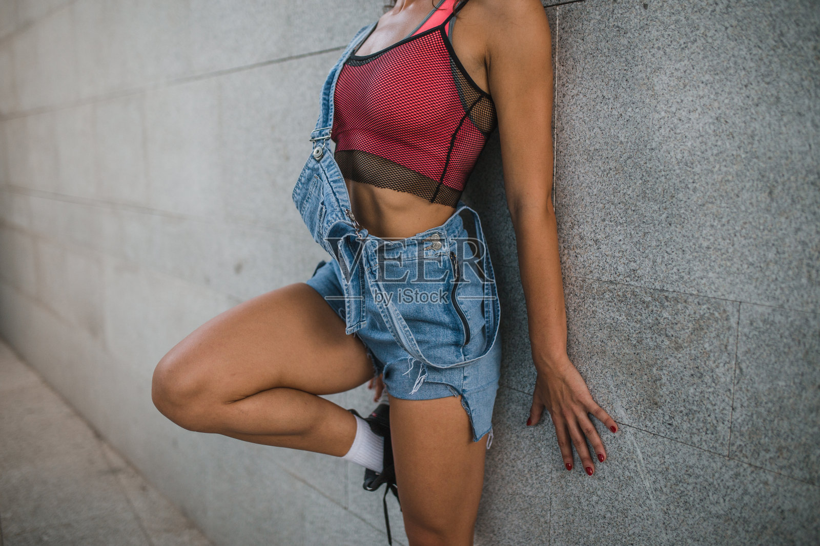 一个穿着背带裤和运动上衣的无法辨认的女人的身体特写照片摄影图片