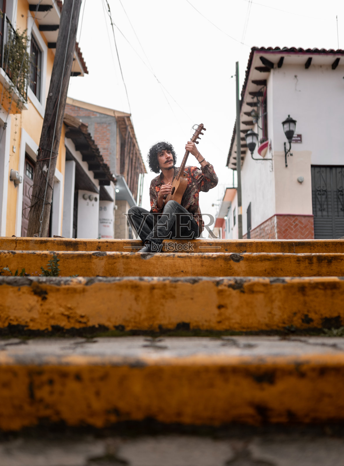 一位年轻的墨西哥音乐家正在街上弹吉拉那吉他照片摄影图片