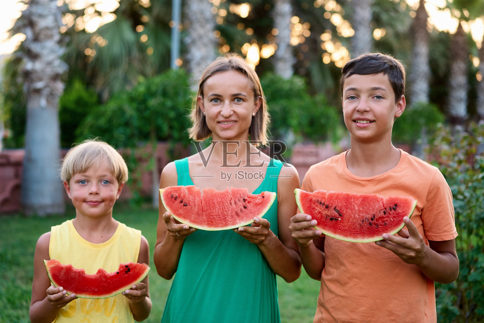 甜蜜的家庭，妈妈和她的孩子在户外吃西瓜，玩得很开心照片摄影图片
