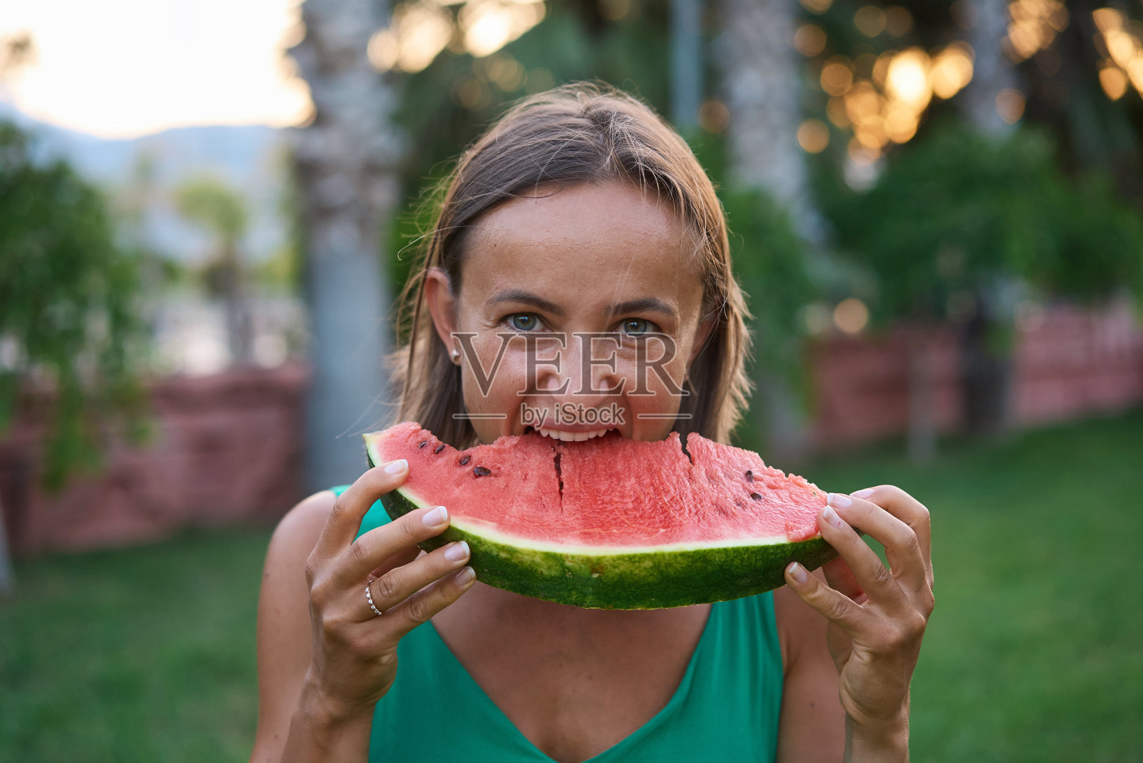 特写的兴奋的年轻女孩在夏天花时间在公园，咬一片西瓜照片摄影图片