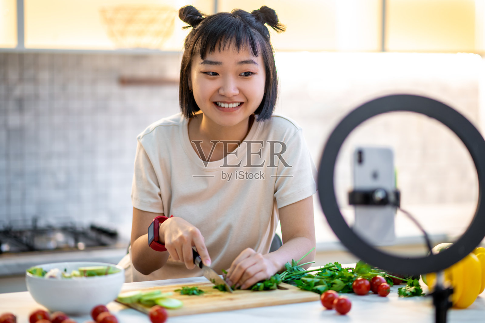 微笑的家庭主妇准备蔬菜沙拉在她的烹饪视频日志照片摄影图片