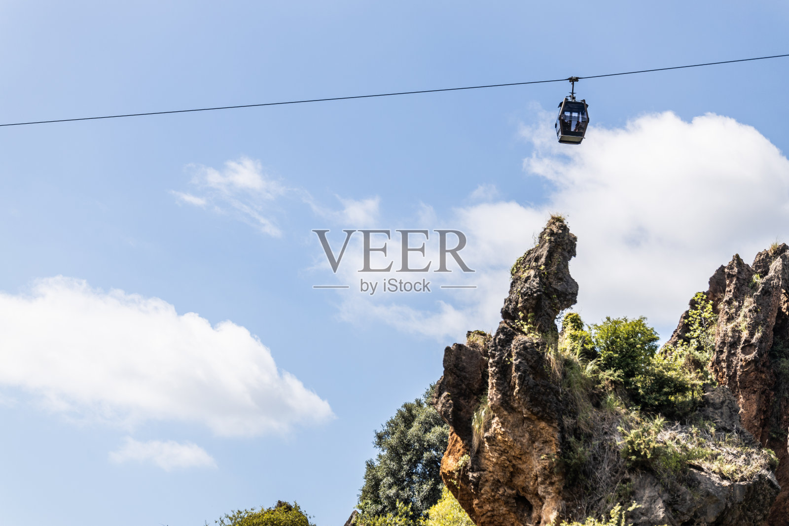 缆车悬挂在美丽的绿色山景之上。照片摄影图片