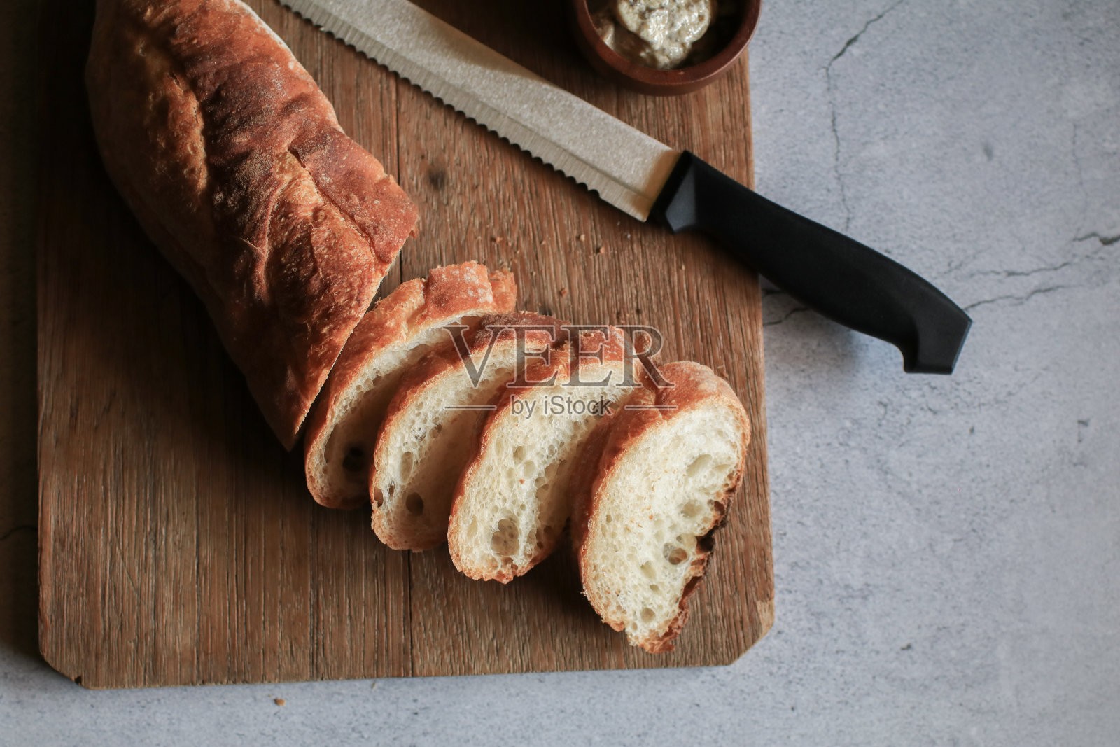 木质切菜板背景上的法国法棍面包。面包包，面包店里美味可口的硬皮面包照片摄影图片
