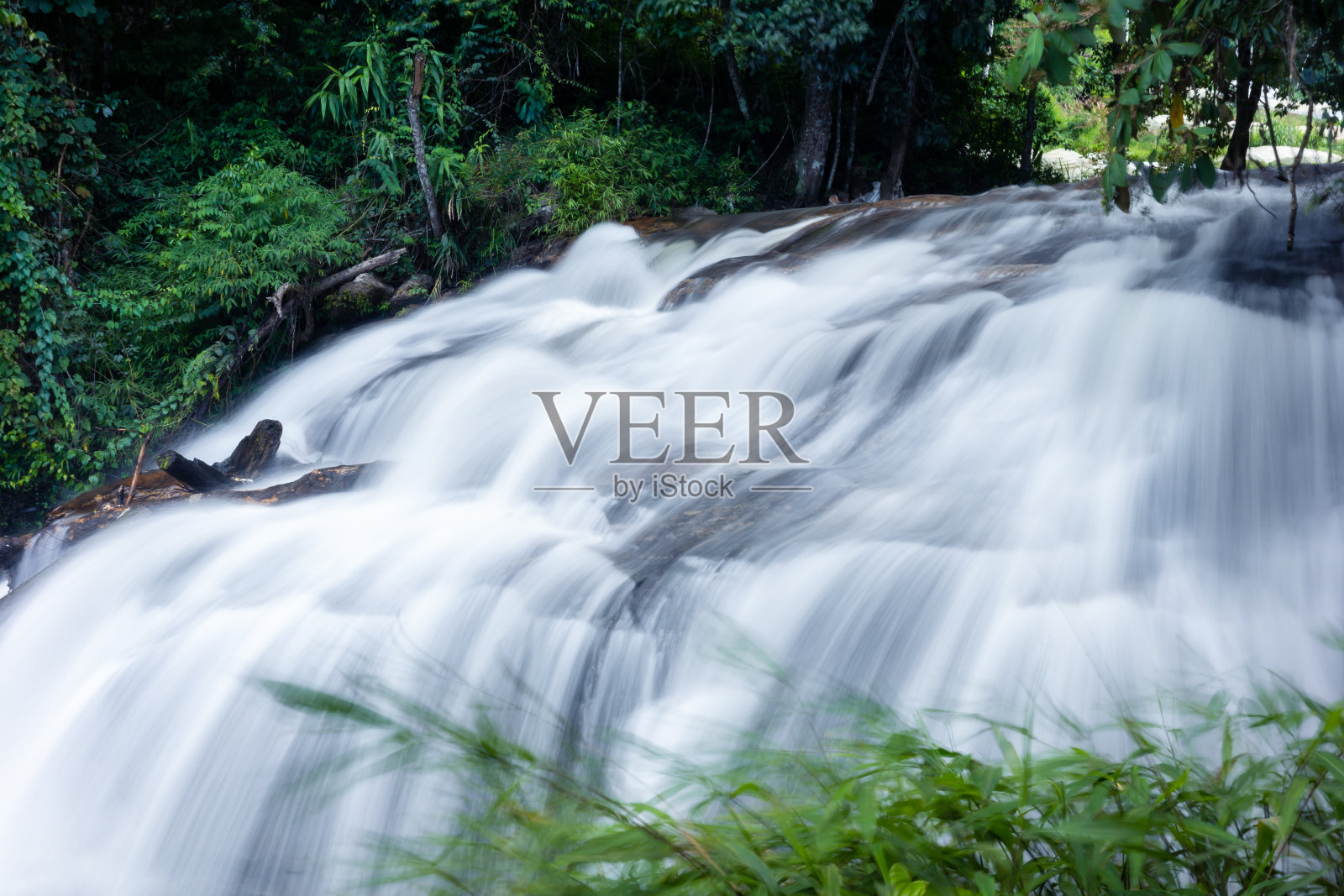 热带雨林瀑布上的强水流。照片摄影图片