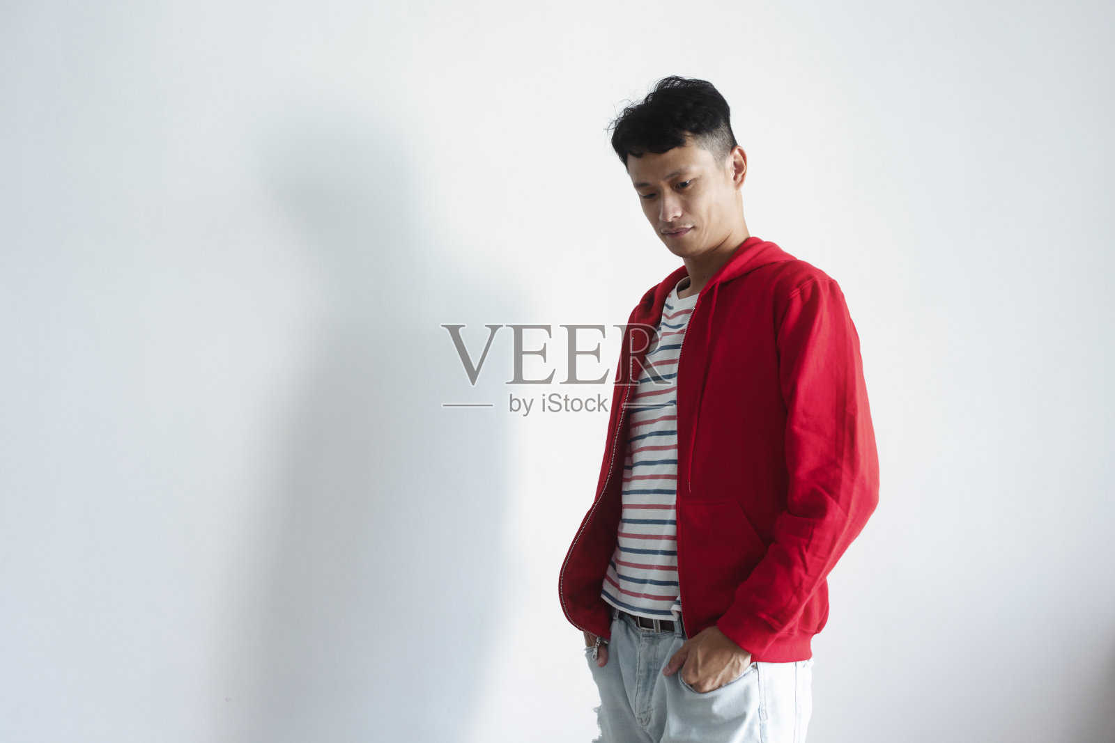 深色的亚洲人在红色夹克的视觉姿势在白色背景。照片摄影图片