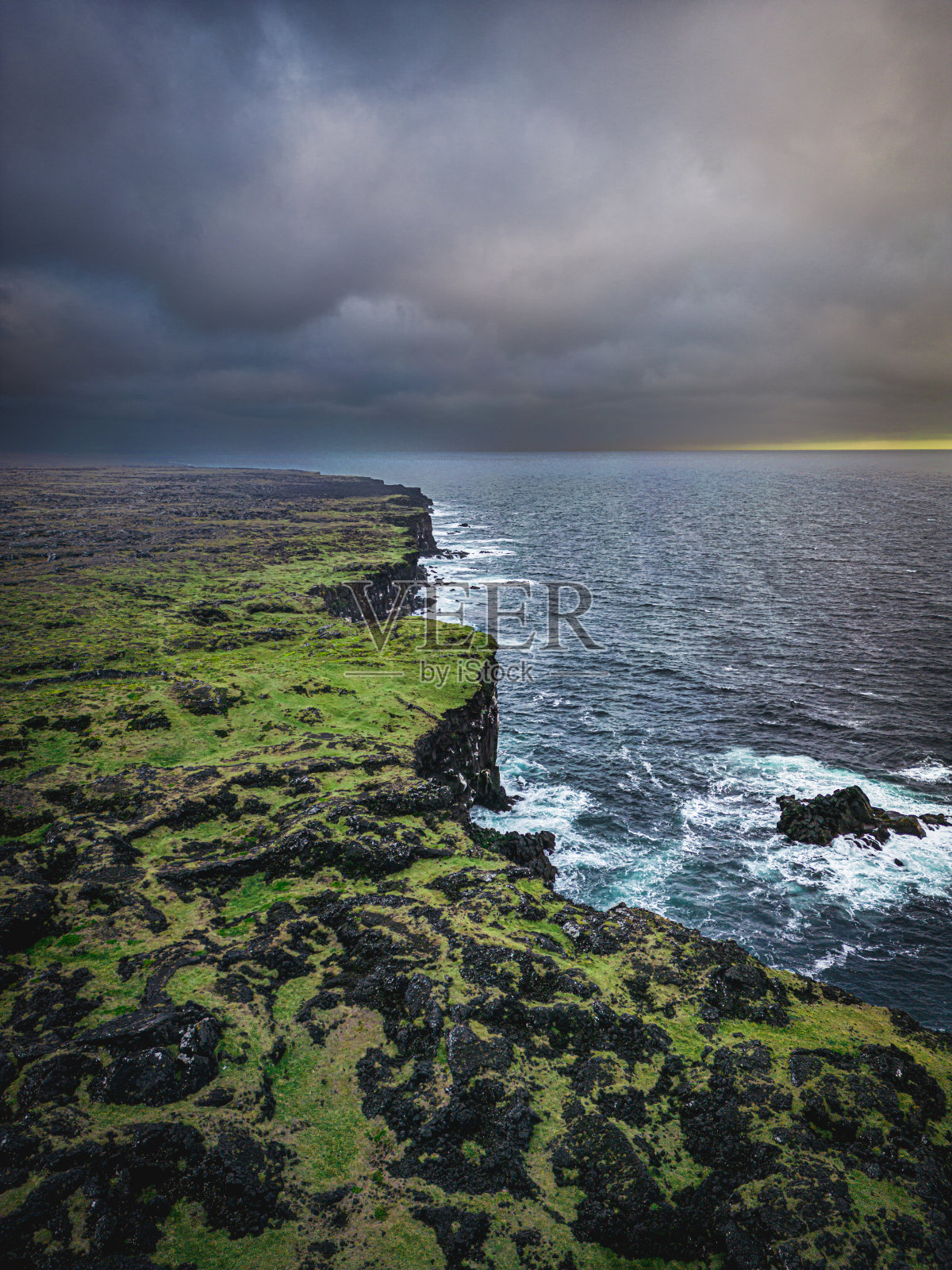 垂直照片的悬崖海岸在日落与黑暗的暴风雨天空在冰岛照片摄影图片