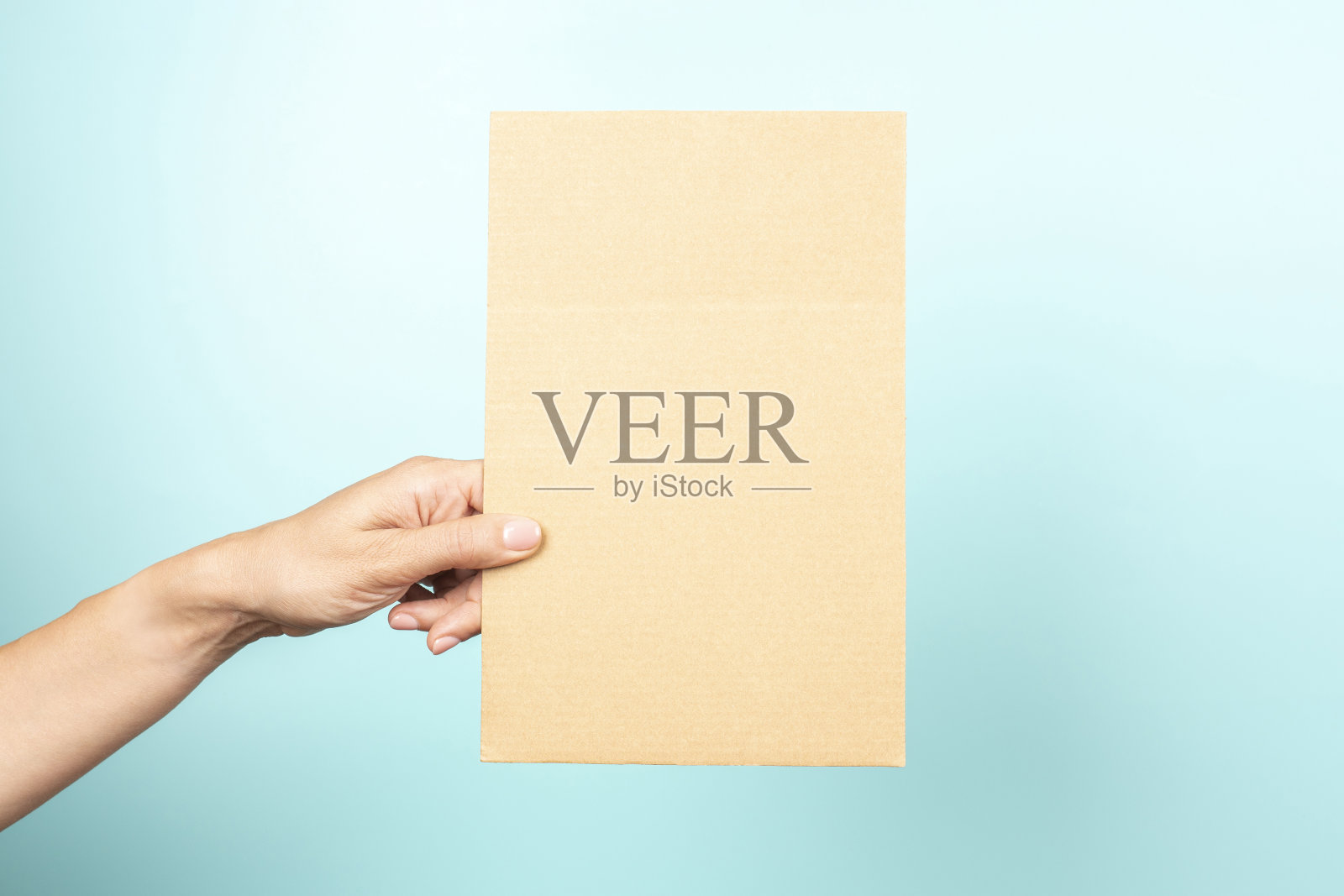 妇女手握空白矩形的棕色纸板上浅蓝色的背景照片摄影图片