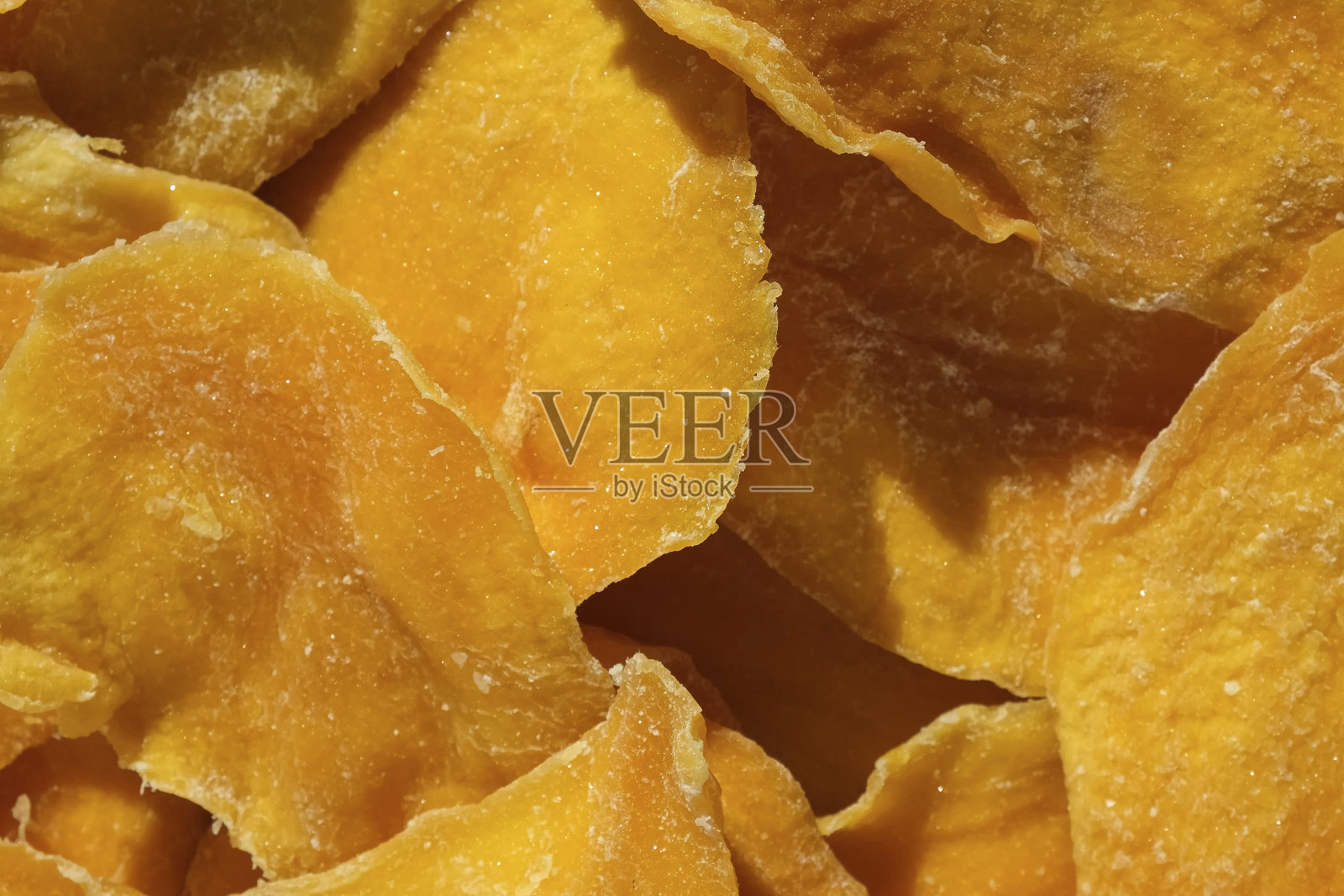 干芒果片特写在一个白色。前视图。特写镜头。芒果芯片背景。脱水脆皮水果片、片。一堆晒干的黄色水果。健康的一餐。俯视图，平铺。照片摄影图片