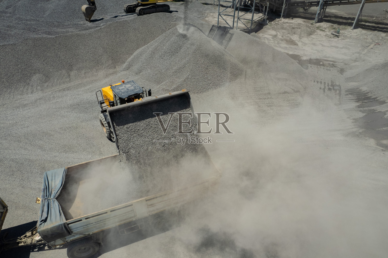 装沙工正在把石头铲进自卸卡车。照片摄影图片