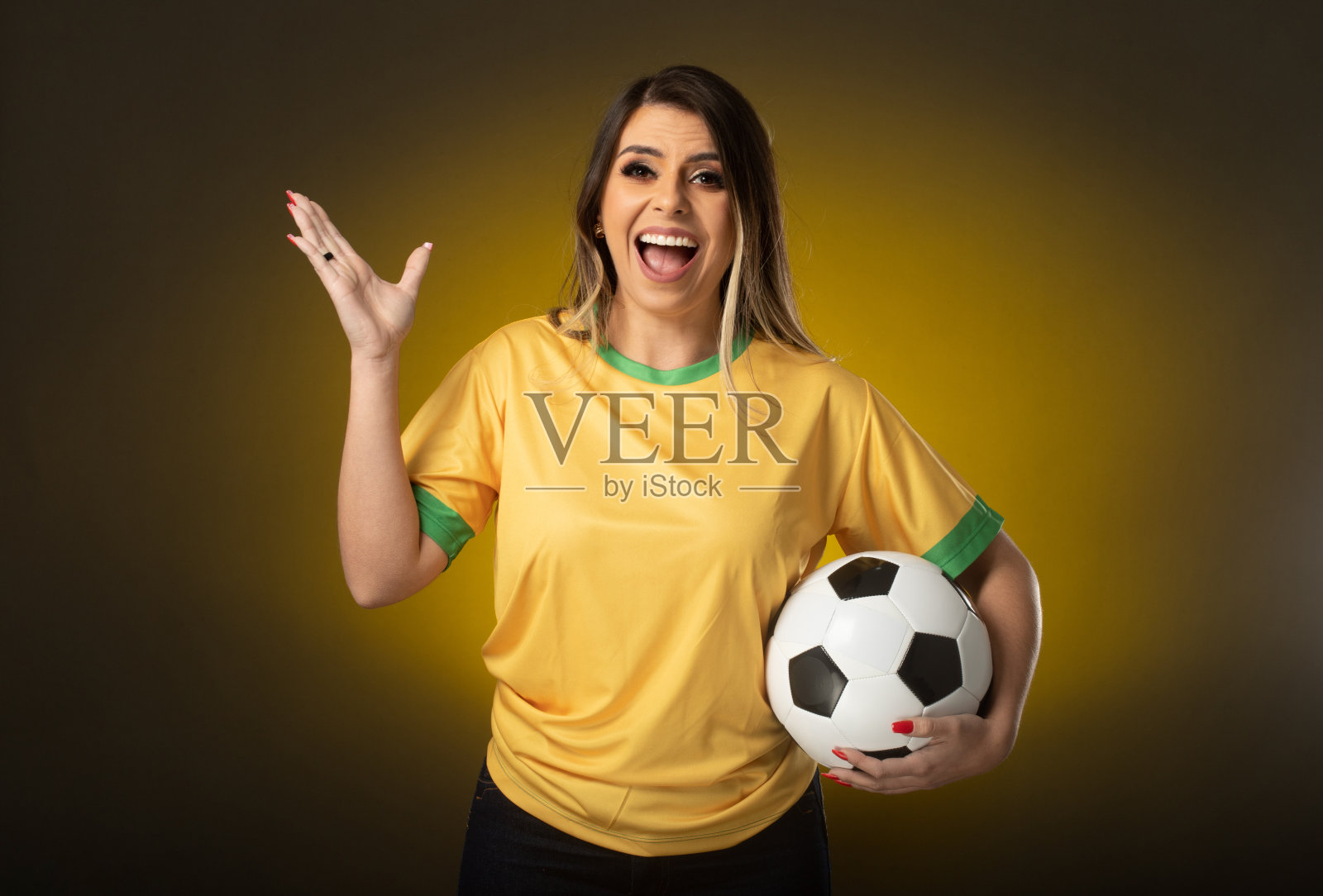 拿着黑板的巴西球迷。在黄色背景的足球或足球比赛中庆祝的女球迷。巴西的颜色照片摄影图片