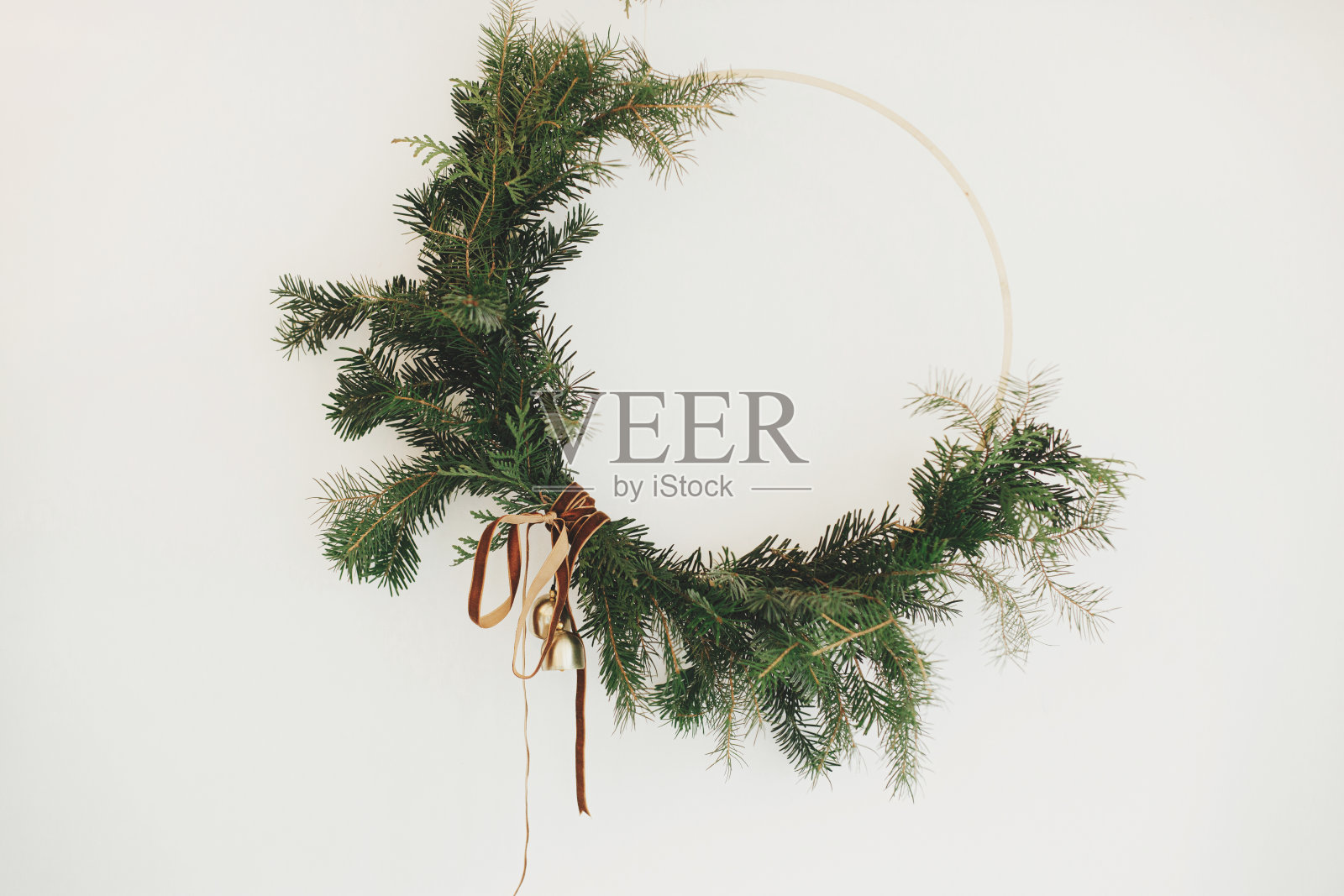 现代波西米亚圣诞花环与天鹅绒丝带和金铃挂在白色的墙壁背景。圣诞快乐，节日快乐!寒假装饰，忧郁形象照片摄影图片