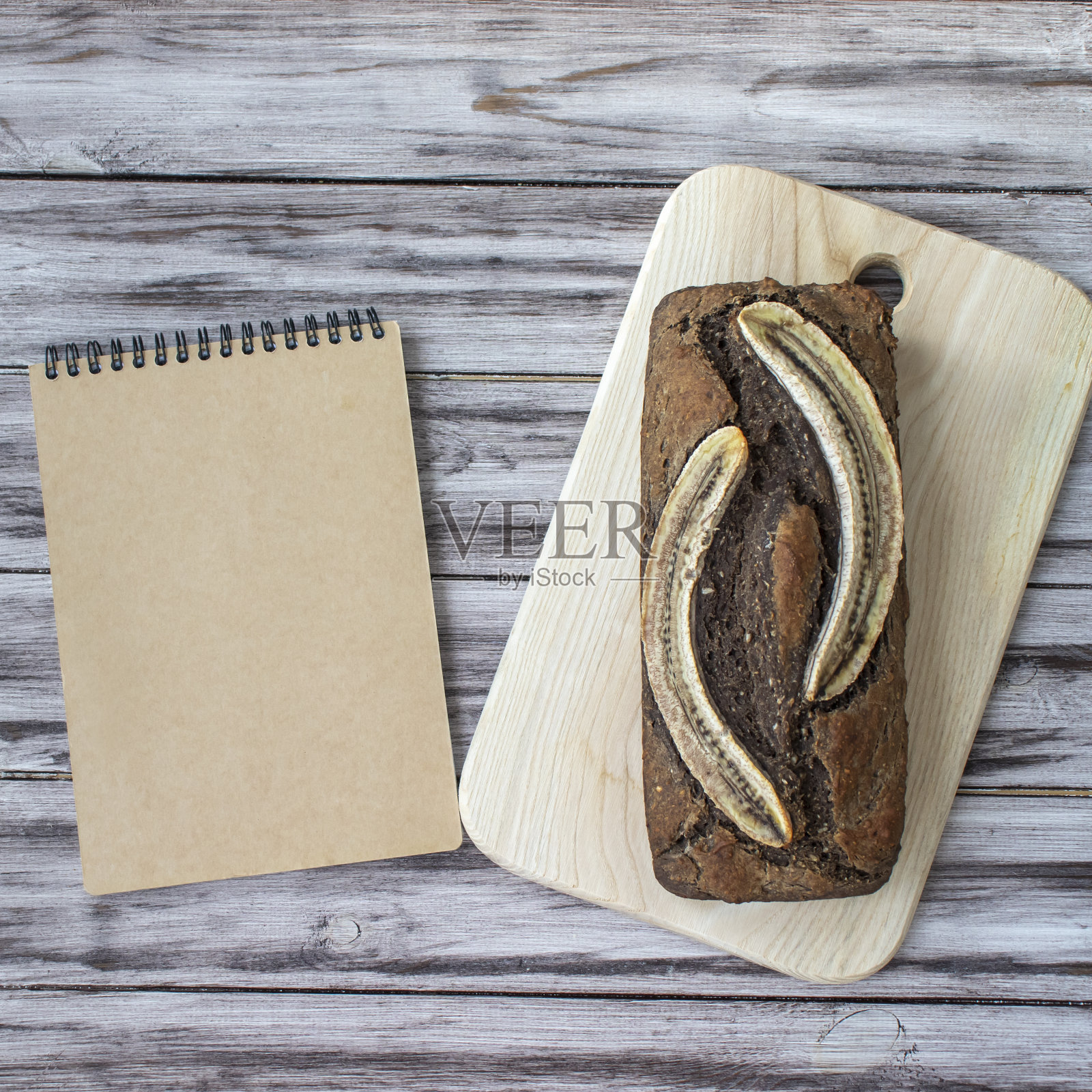 自制香蕉面包放在木制背景上，空白记事本上写着食谱或名字。平铺，俯视图，复制空间照片摄影图片
