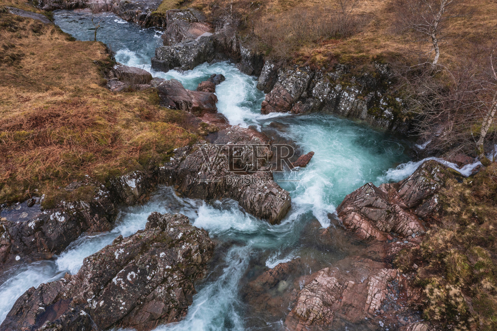 壮观的空中无人机景观图像，生机勃勃的科河在苏格兰高地的雪山下流动照片摄影图片