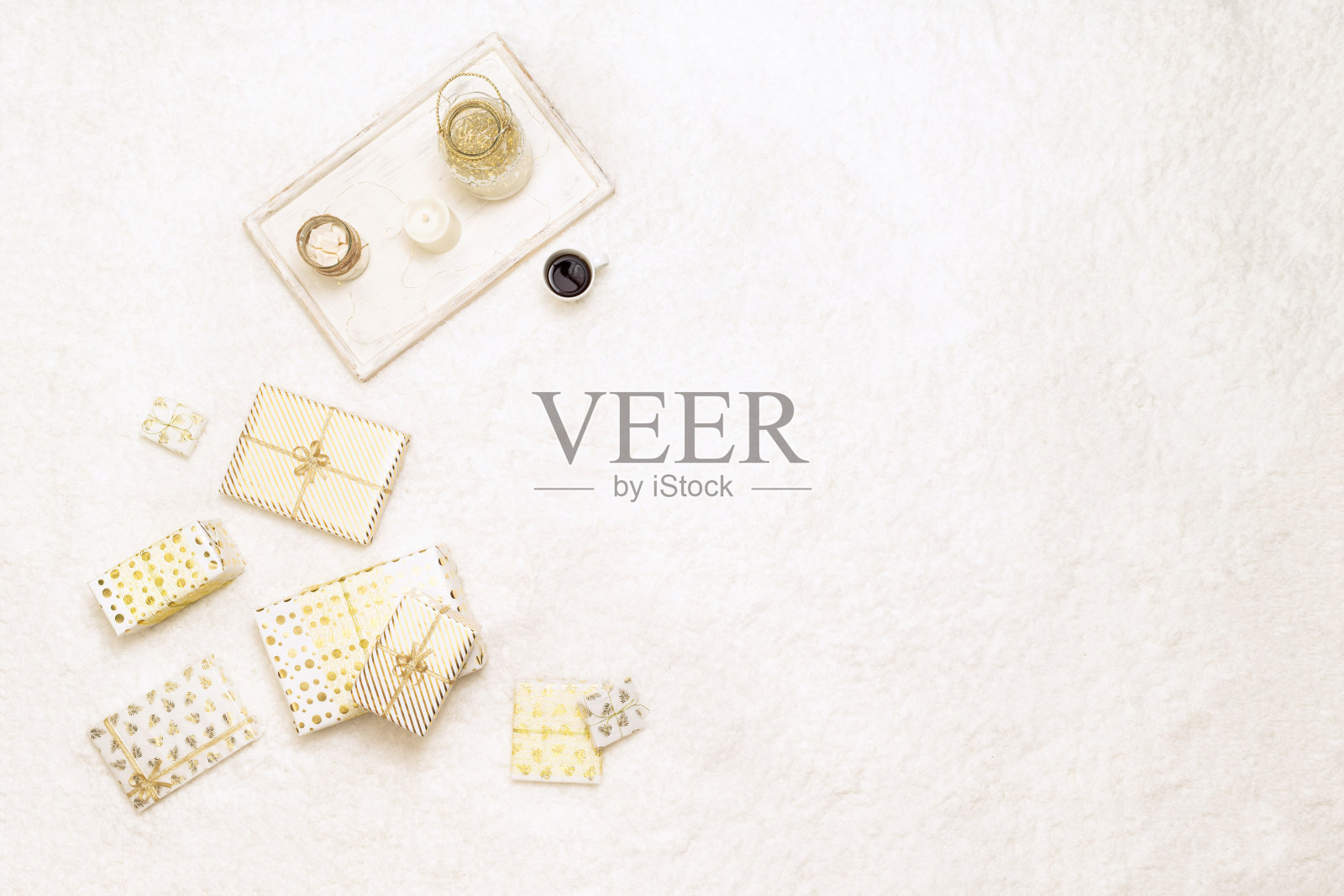 圣诞礼品盒包裹在白色的金色纸，为家庭躺在蓬松的雪白地毯托盘杯热巧克力和棉花糖。副本的空间。俯视图照片摄影图片