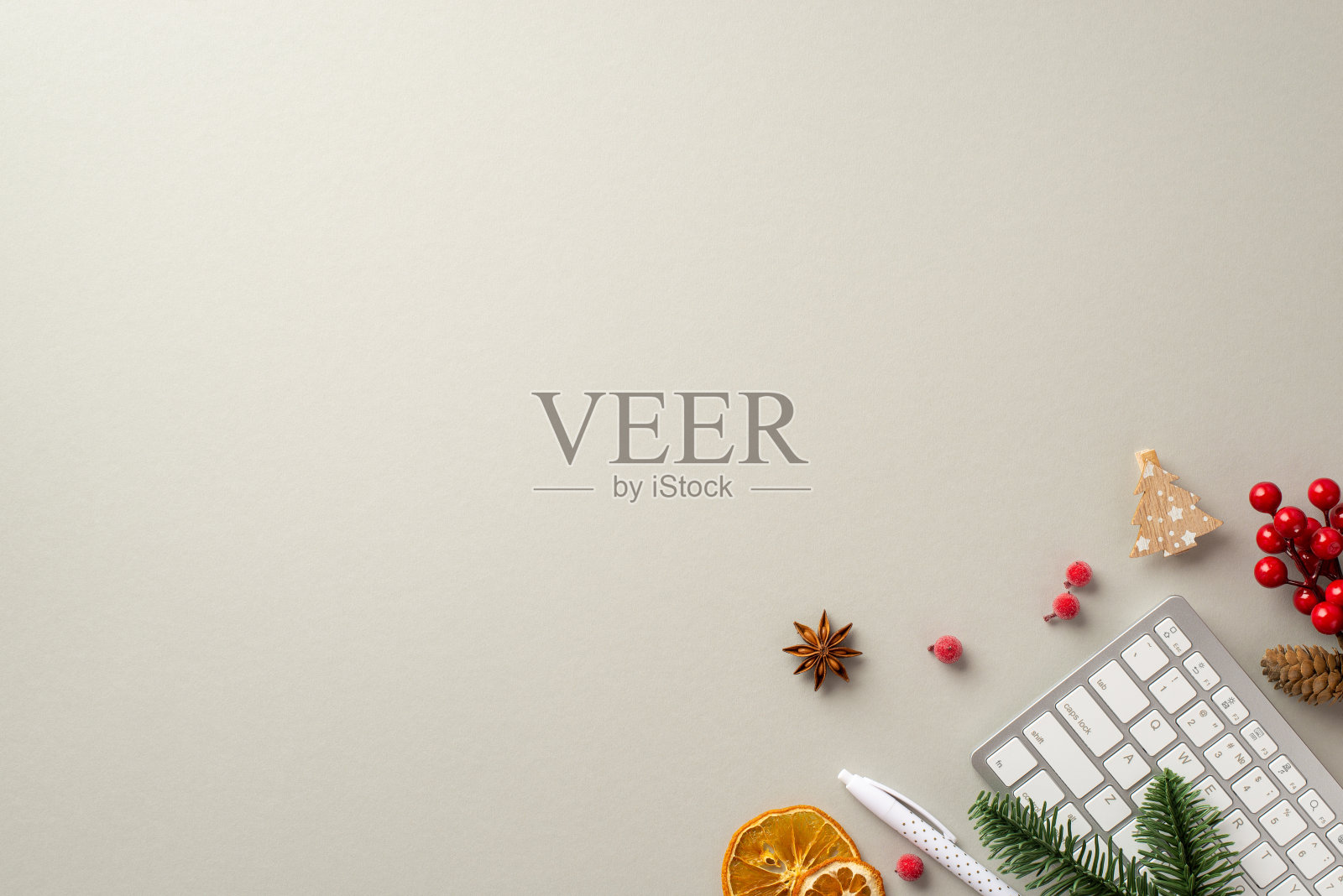 新年的概念。顶视图照片工作站键盘钢笔圣诞树木材装饰槲寄生浆果松枝干橙片和八角上孤立的灰色背景与copyspace照片摄影图片