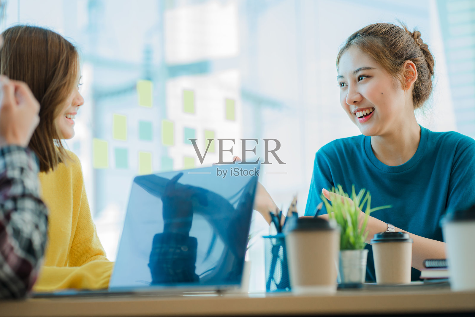 亚洲创意团队围坐在一起，在工作坊中分享灵感创意。年轻的现代商人在工作场所开会时使用的是绘图纸和笔记本电脑。照片摄影图片