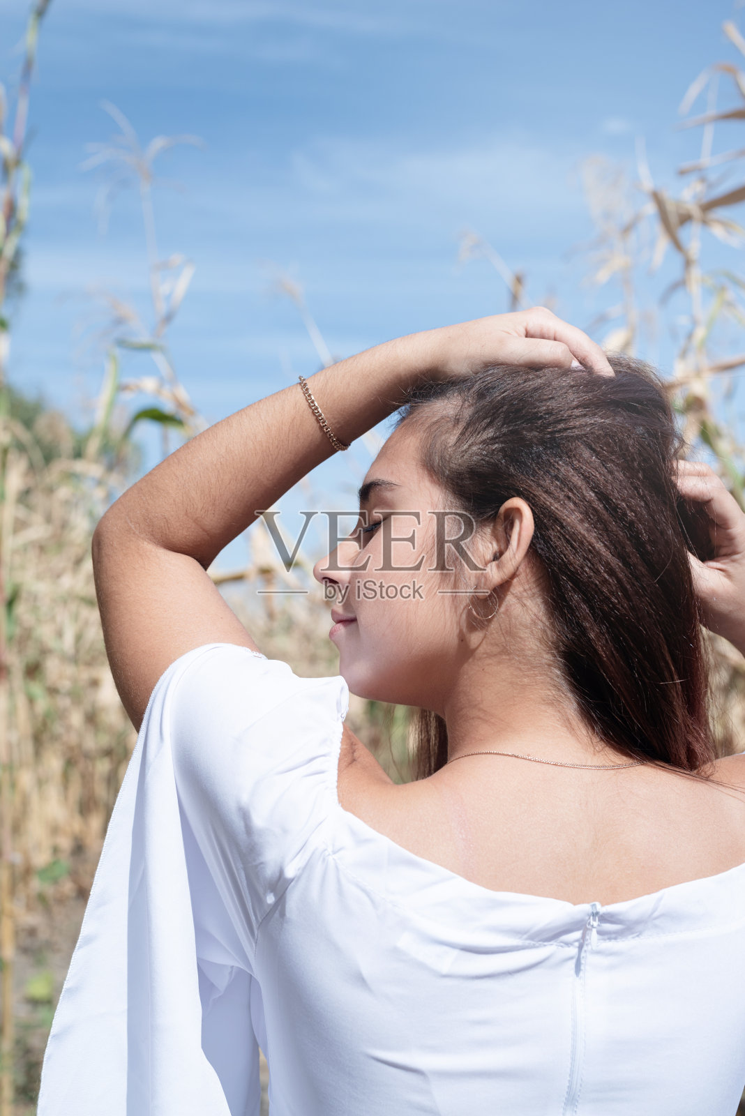 欢快的白人妇女穿着白色的衣服在玉米作物，天空背景照片摄影图片