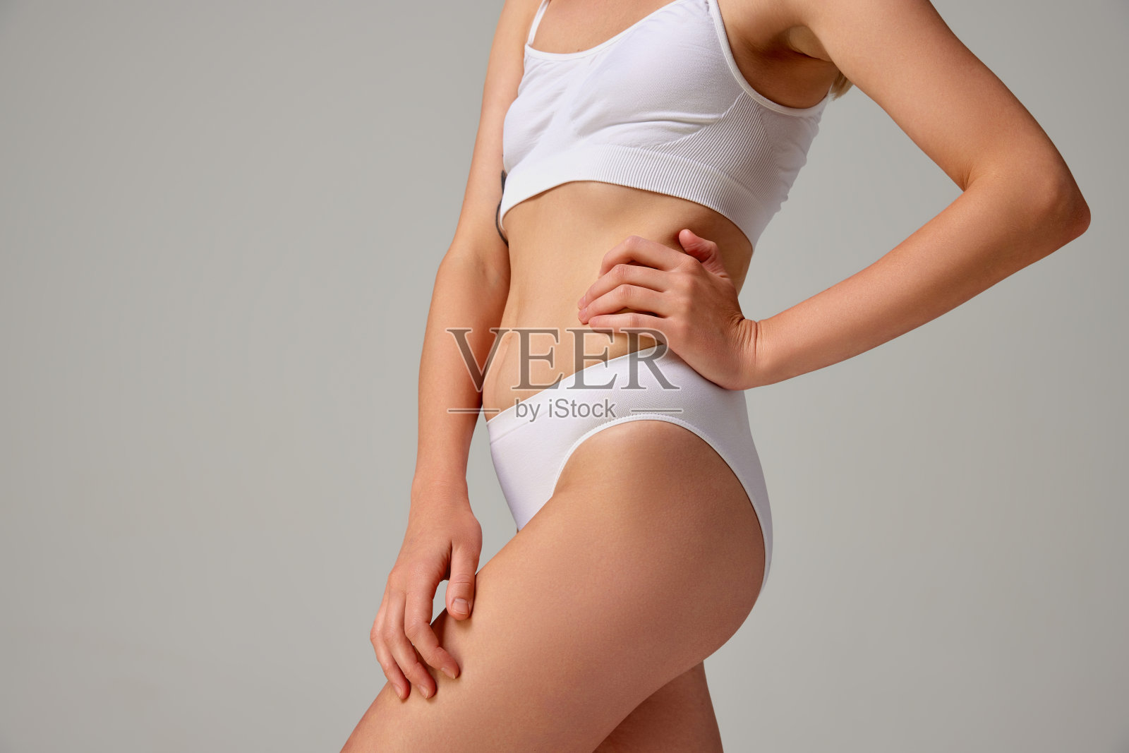 运动的女性身体在白色内衣孤立的灰色工作室背景裁剪的图像。运动的生活方式照片摄影图片