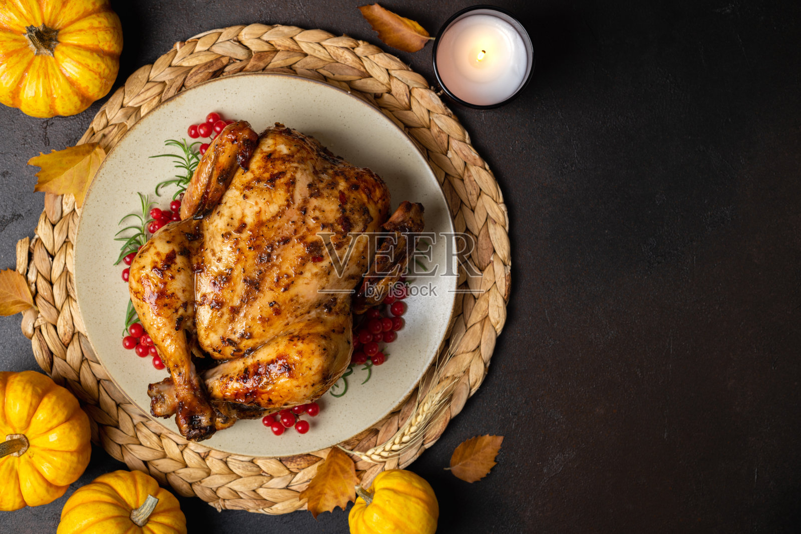 感恩节烤鸡：黑桌上的烤鸡或火鸡与香草迷迭香、浆果和南瓜感恩节晚餐，节日餐桌布置照片摄影图片
