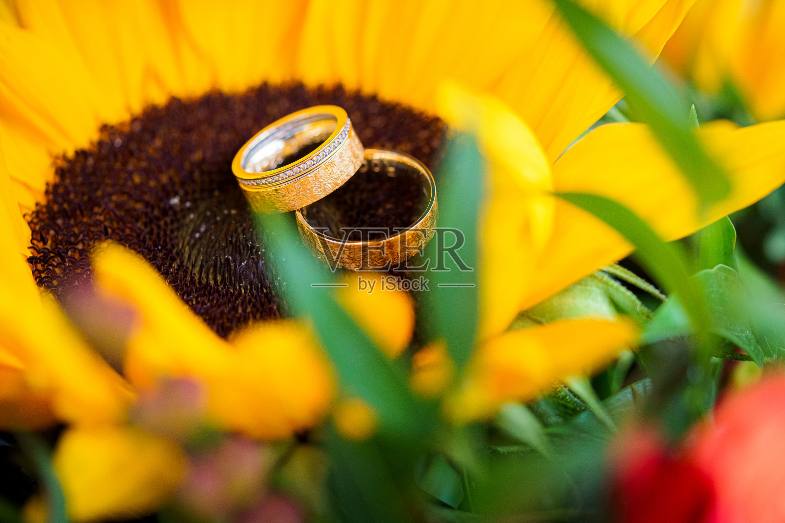 黄色新娘花束上的结婚戒指。照片摄影图片
