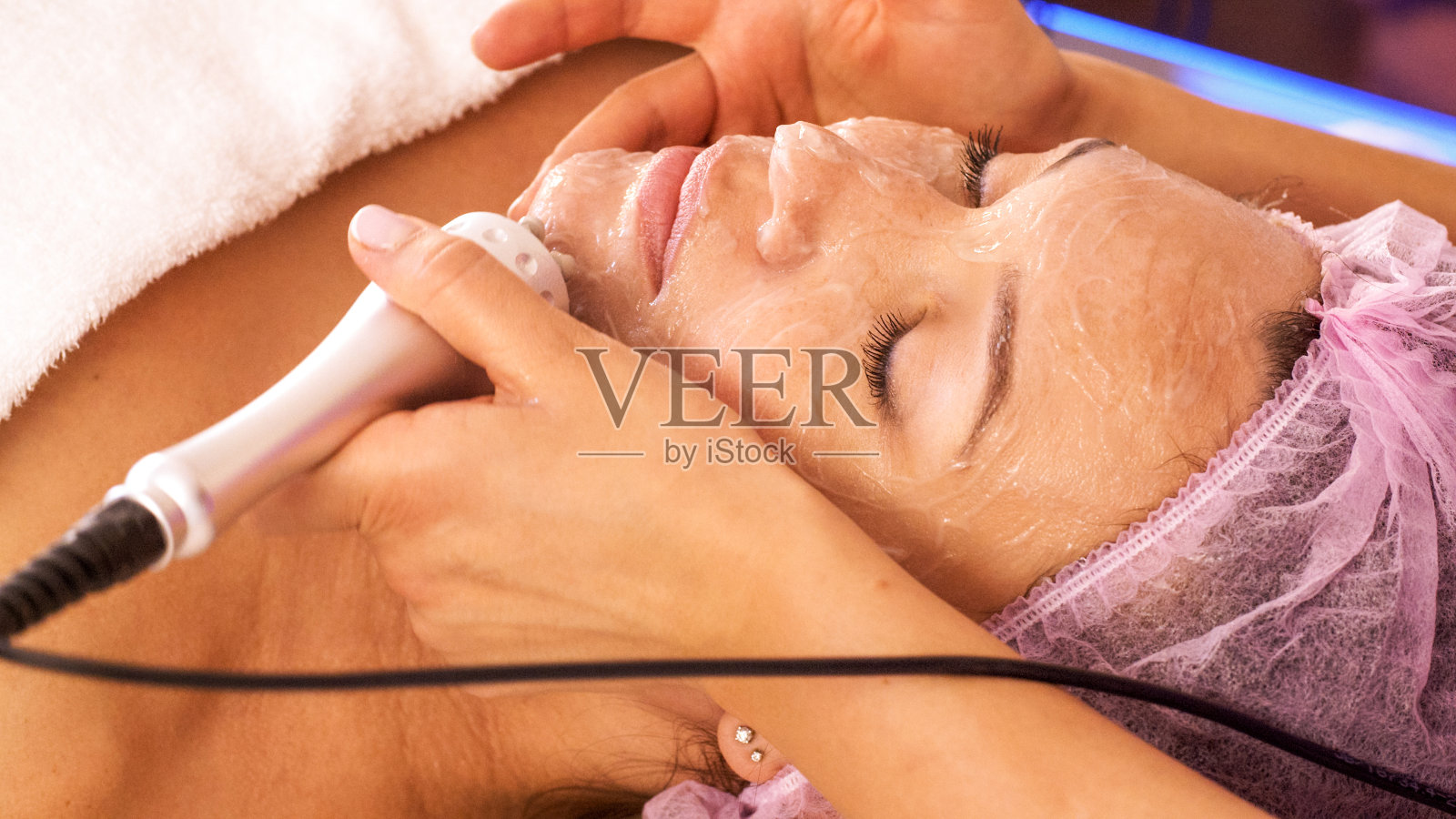 一名女子在水疗沙龙接受面部美容护理。美容师使用医疗设备进行医疗程序。美容师给女人做整容手术。照片摄影图片