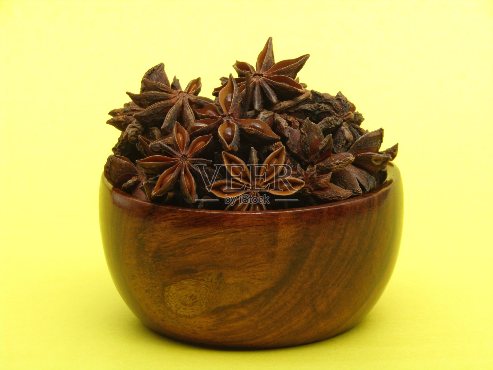 八角装在黄色背景的木碗里照片摄影图片