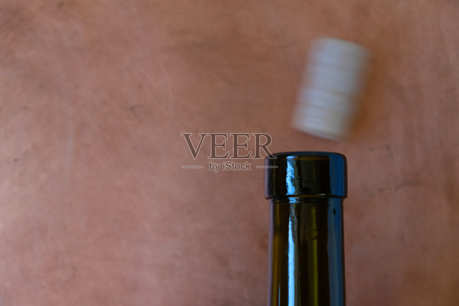 空酒瓶的瓶口和模糊的软木塞在铜背景上运动。照片摄影图片