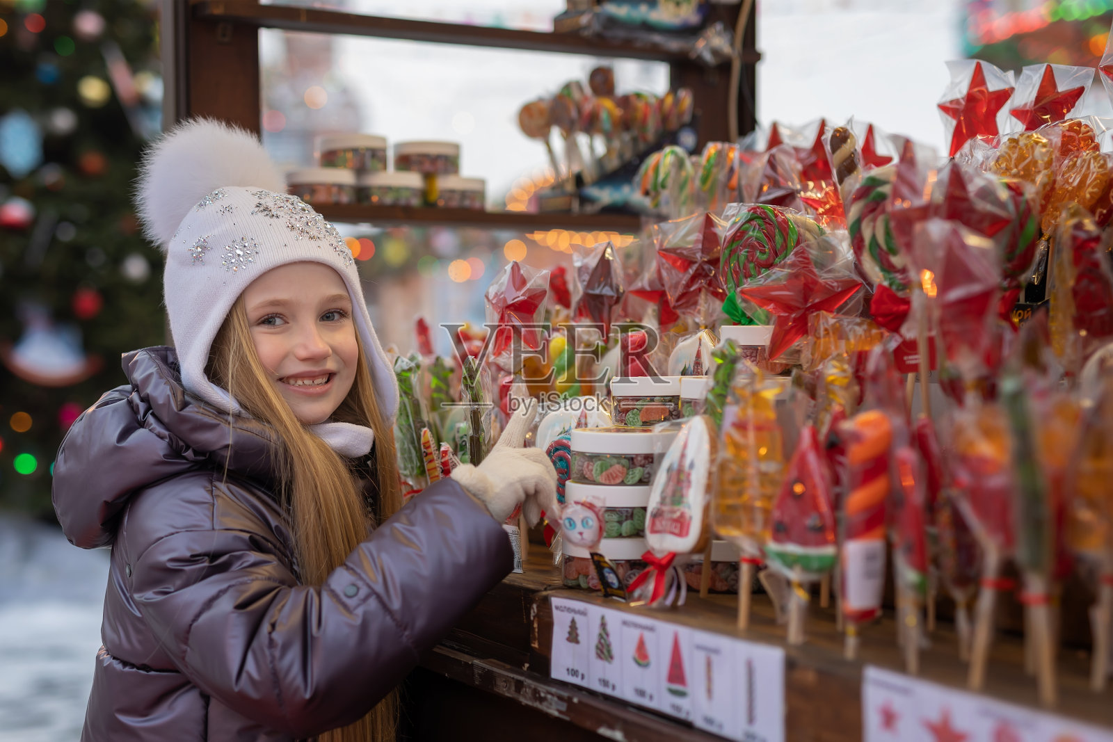 女孩在圣诞市场上看、选、买焦糖、棒棒糖和糖果照片摄影图片