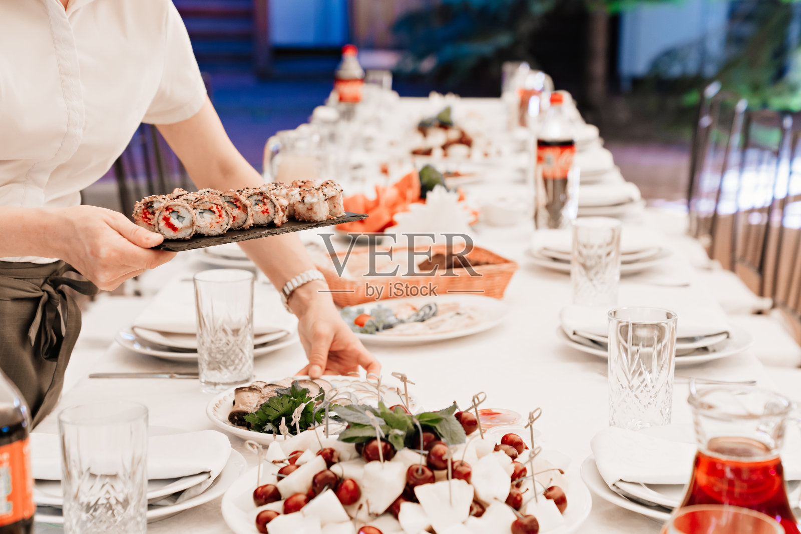 服务员在桌子上放了一个黑色的托盘，里面装着日式烤面包卷。照片摄影图片