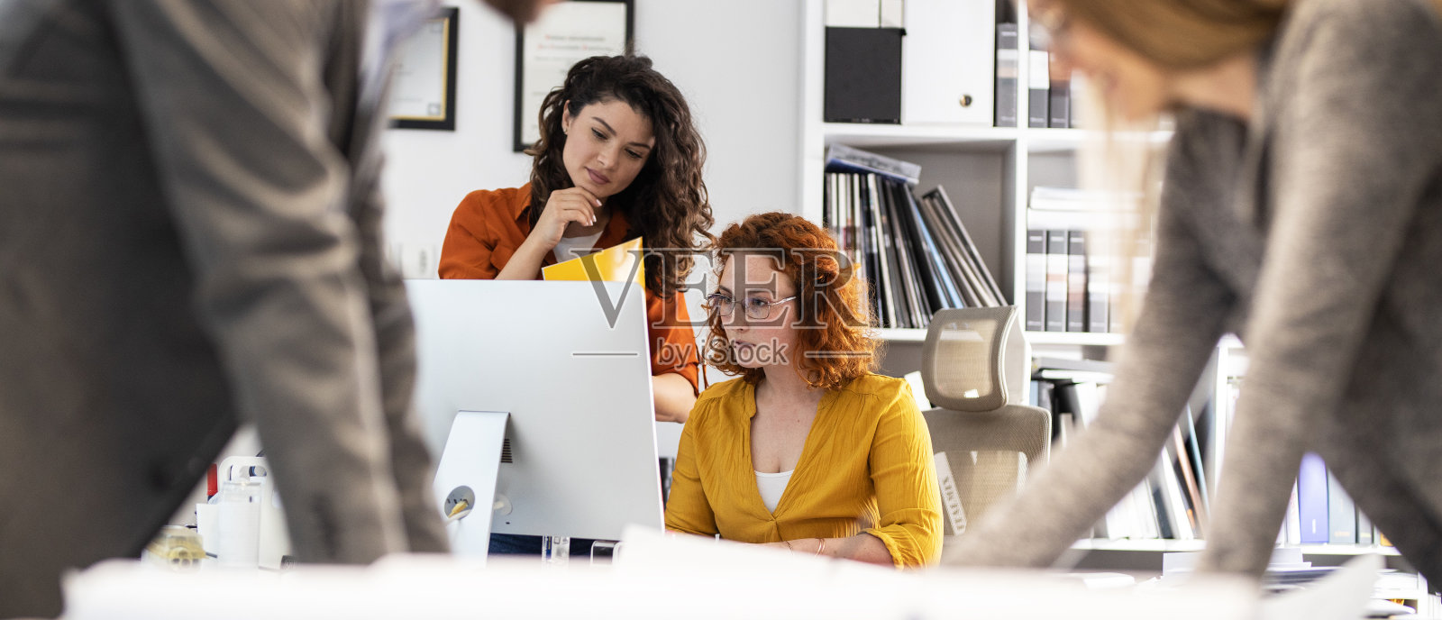 两个女同事正试图解决一个新项目的问题。他们站在桌子旁边看蓝图。在办公室的工作日。照片摄影图片