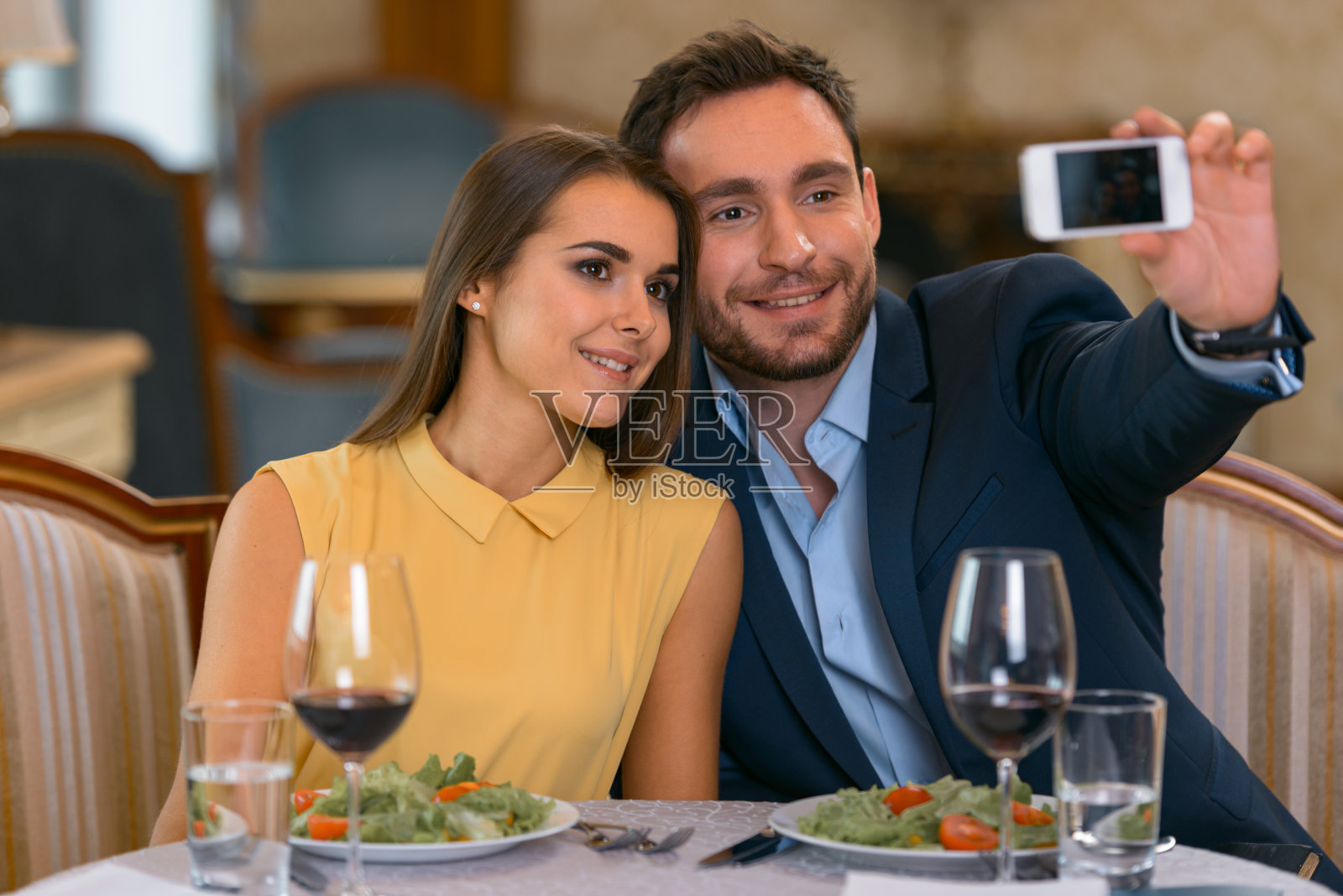年轻夫妇在昂贵的酒店吃浪漫的晚餐，用手机自拍照片摄影图片