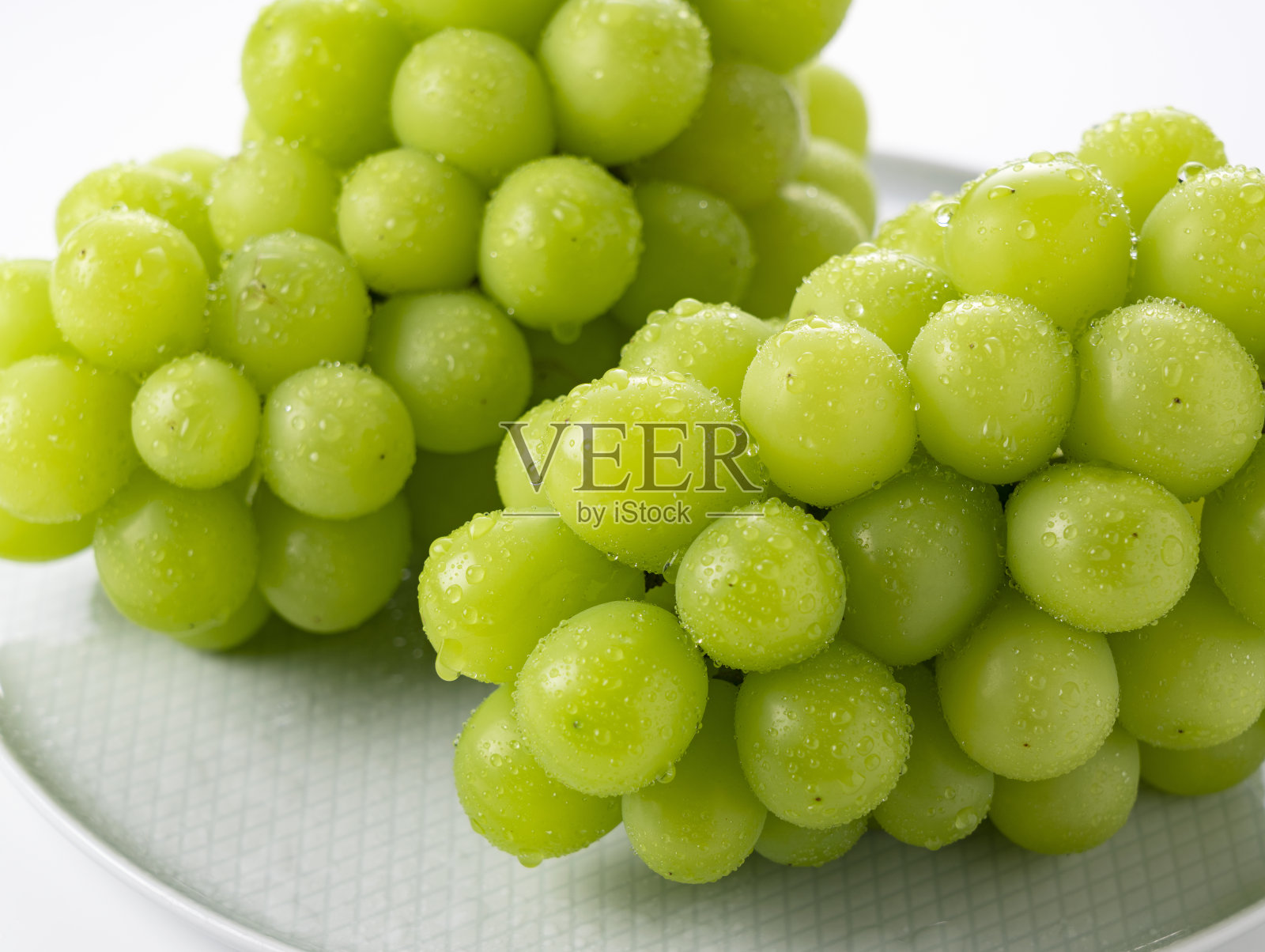 将麝香葡萄酒与水滴放在白色背景的盘子上。照片摄影图片