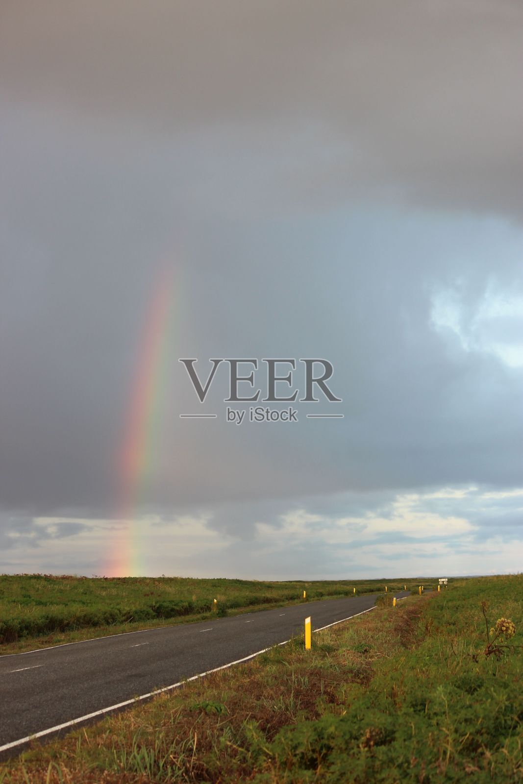 在冰岛，一条柏油路在白天垂直拍摄，上面有彩虹照片摄影图片