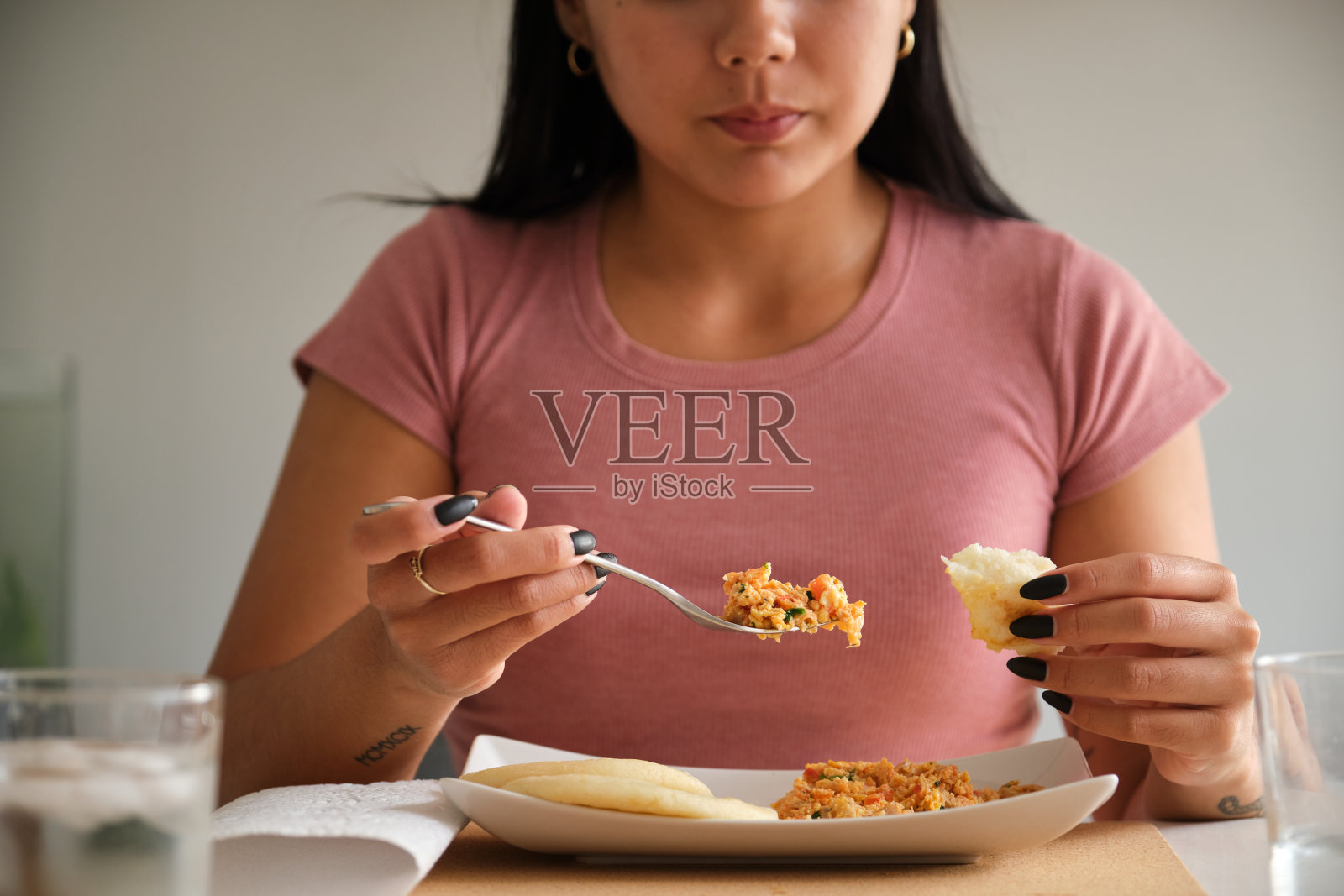 一个吃传统玉米饼的年轻拉丁女子的特写镜头。照片摄影图片