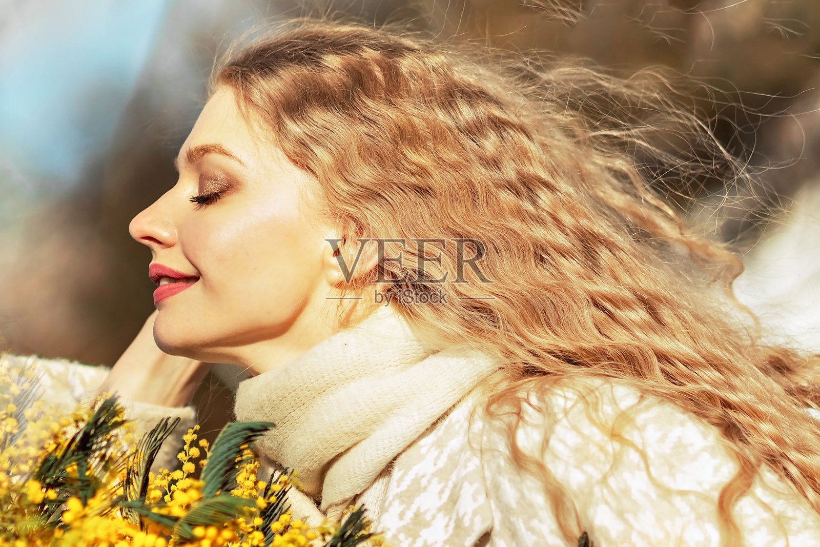 一位金发年轻女子的肖像，手里拿着一束含羞草。春天照片摄影图片