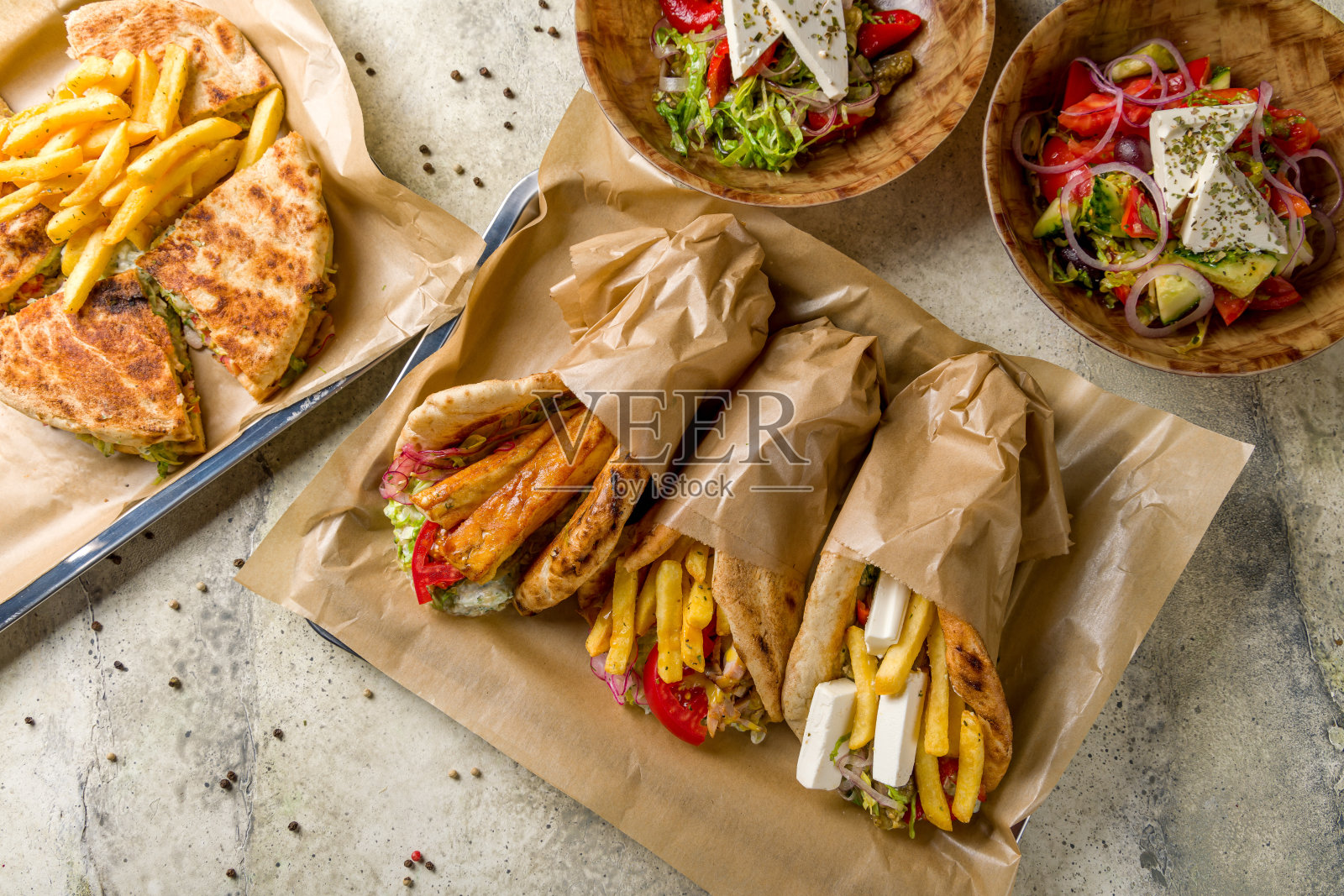 鸡肉意大利面，什锦陀螺仪，鸡肉陀螺仪，羊乳酪陀螺仪，咸味奶酪陀螺仪，石头桌上的希腊沙拉，希腊美食照片摄影图片