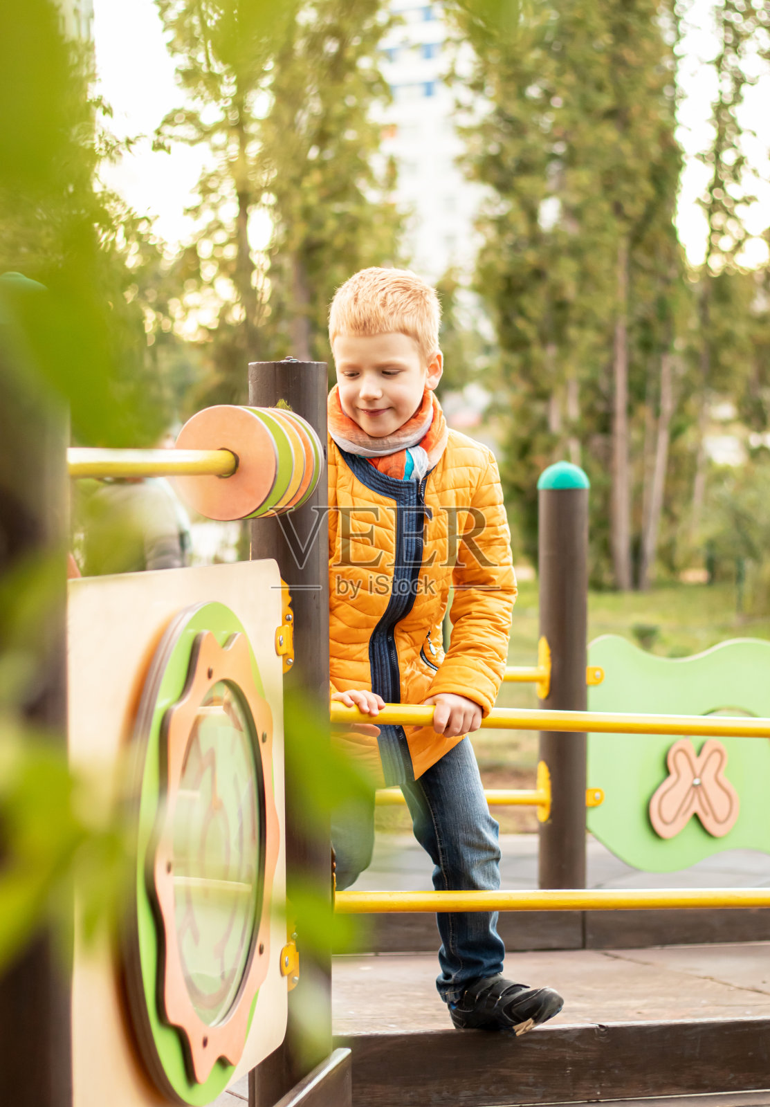 红头发，穿着黄色衣服的快乐少年在城市公园的现代操场上散步玩耍照片摄影图片