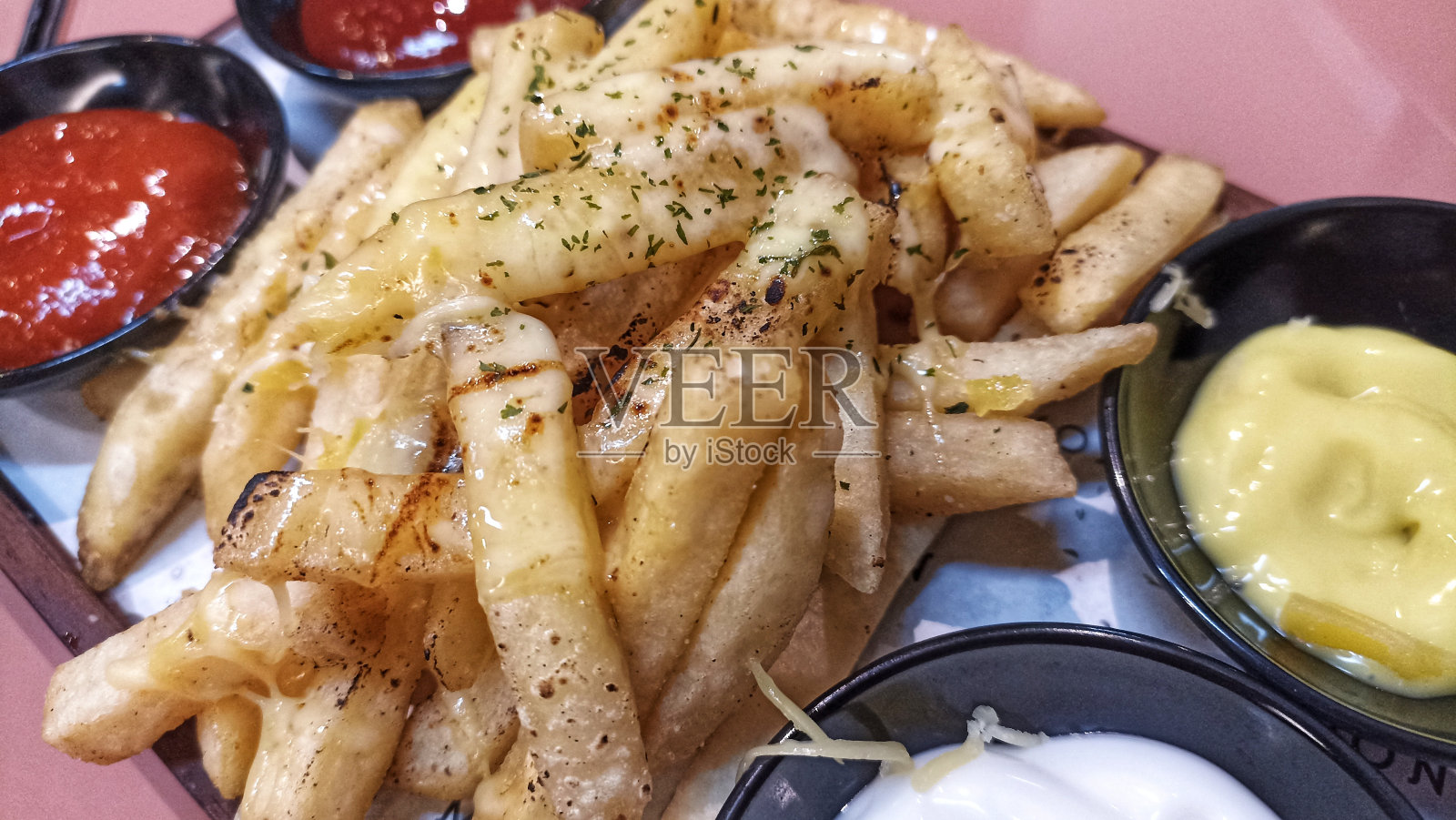 在小碗里淋上蛋黄酱，撒上欧芹粉和芝士酱的薯条。照片摄影图片
