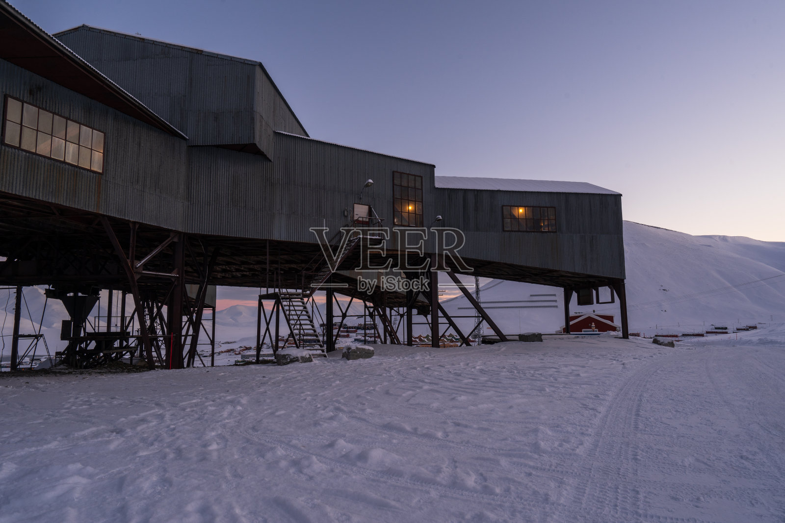 在一个寒冷的雪天的黄昏，朗伊尔城废弃的缆车中心(Taubanesentralen)。照片摄影图片