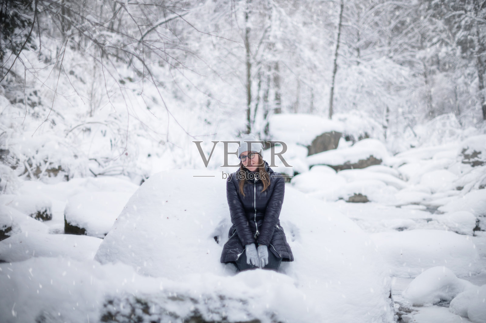 走在白雪覆盖的冬日森林里的女人照片摄影图片