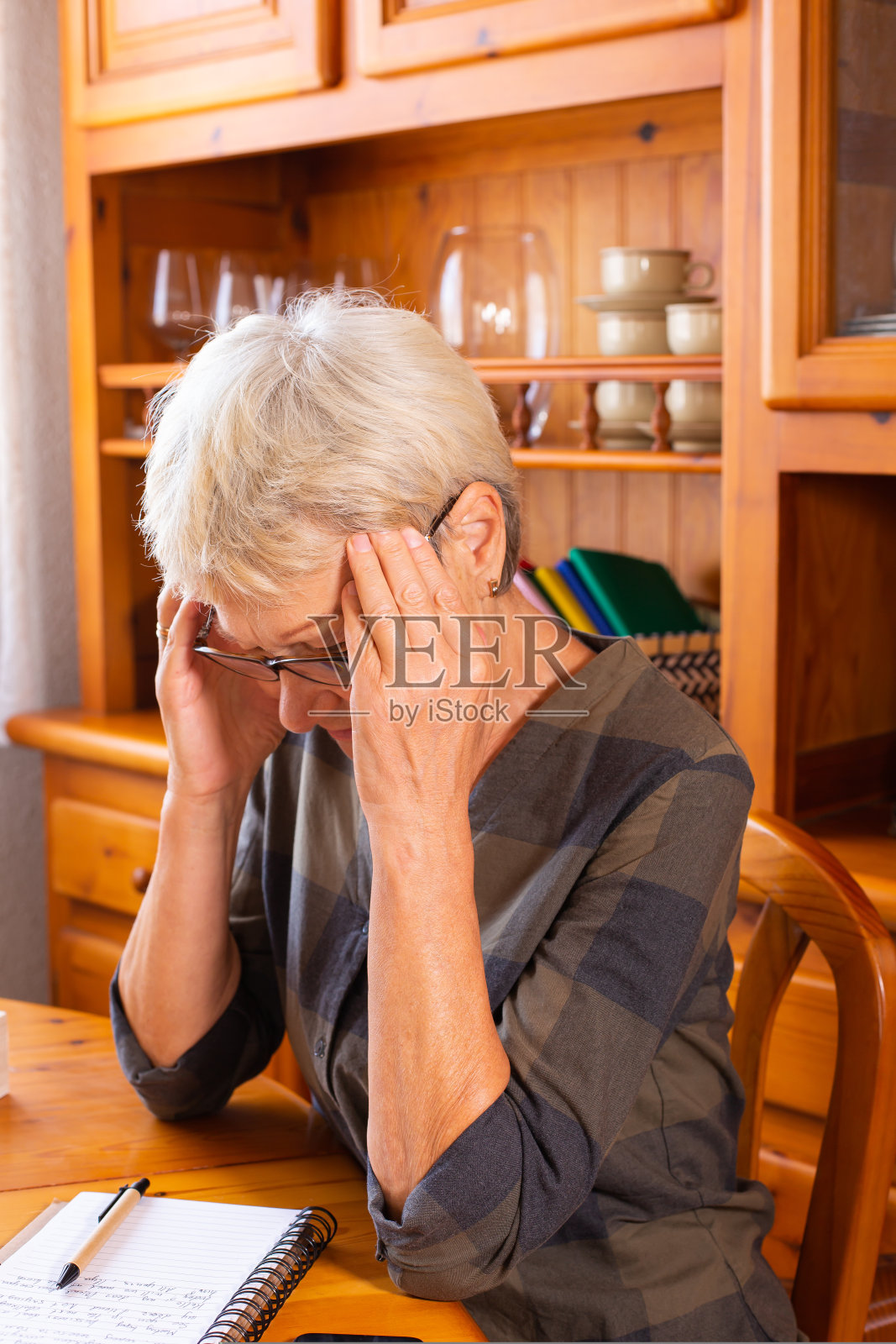 老年妇女在做笔记时头痛照片摄影图片