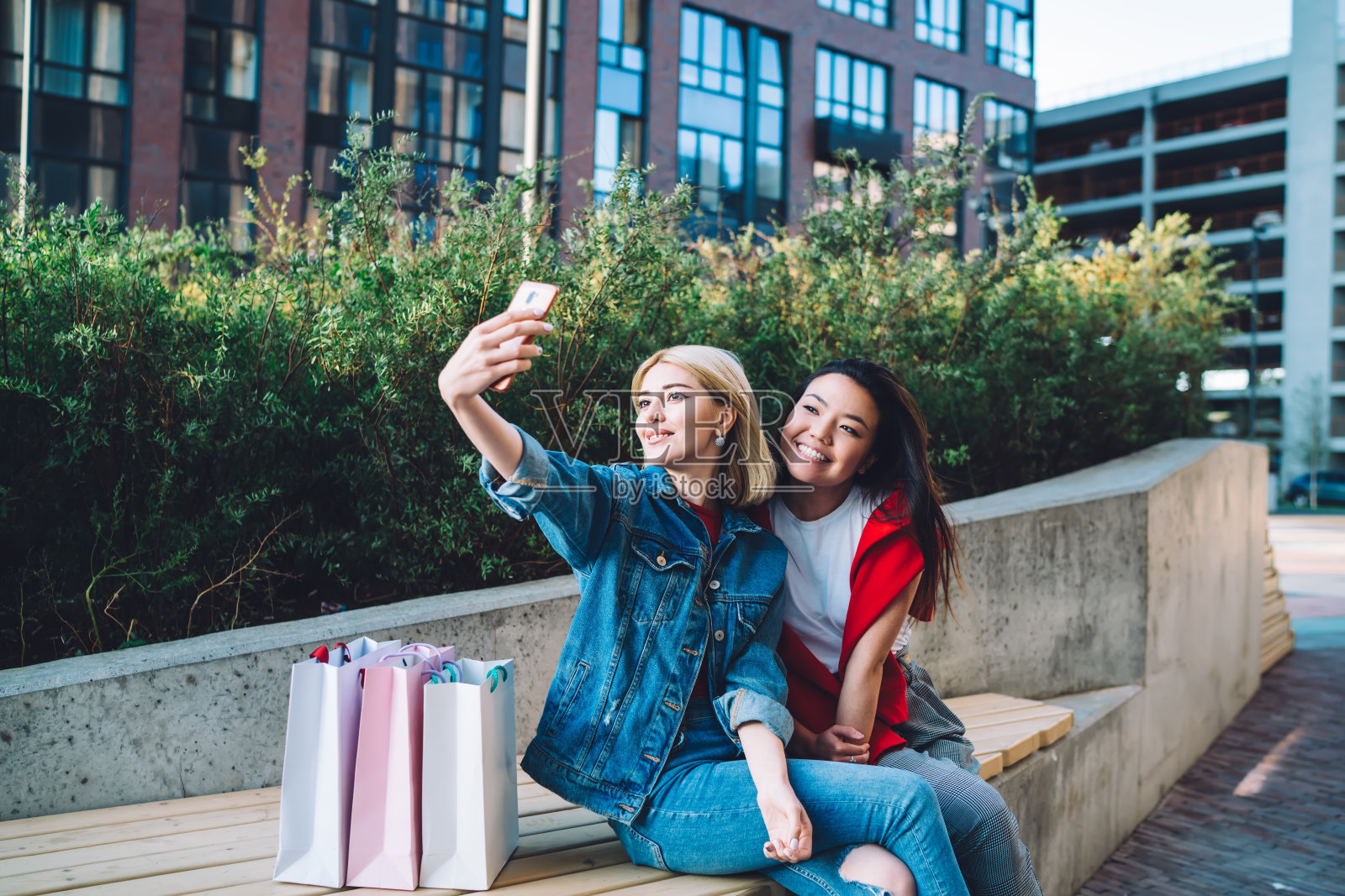 满意的多民族大学女生在城市街道上用智能手机自拍照片摄影图片