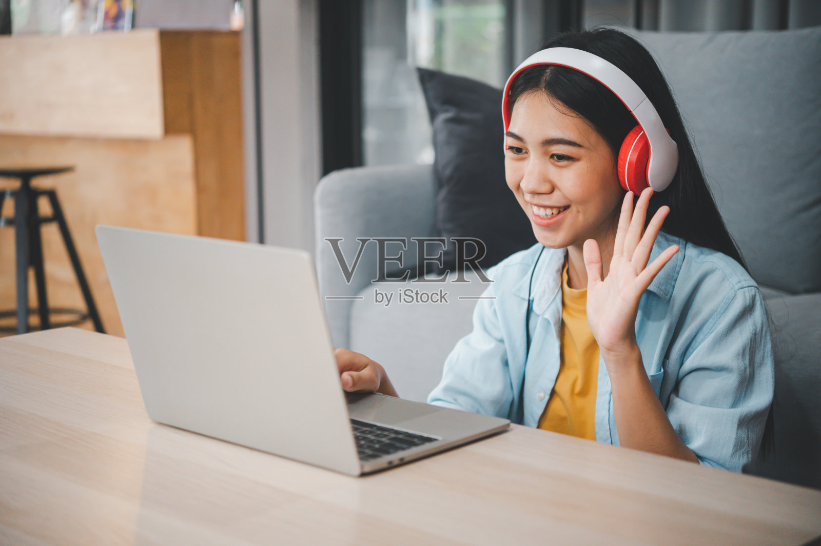 年轻的学生戴着耳机在线学习，通过视频通话，在家里的沙发上进行远程学习照片摄影图片