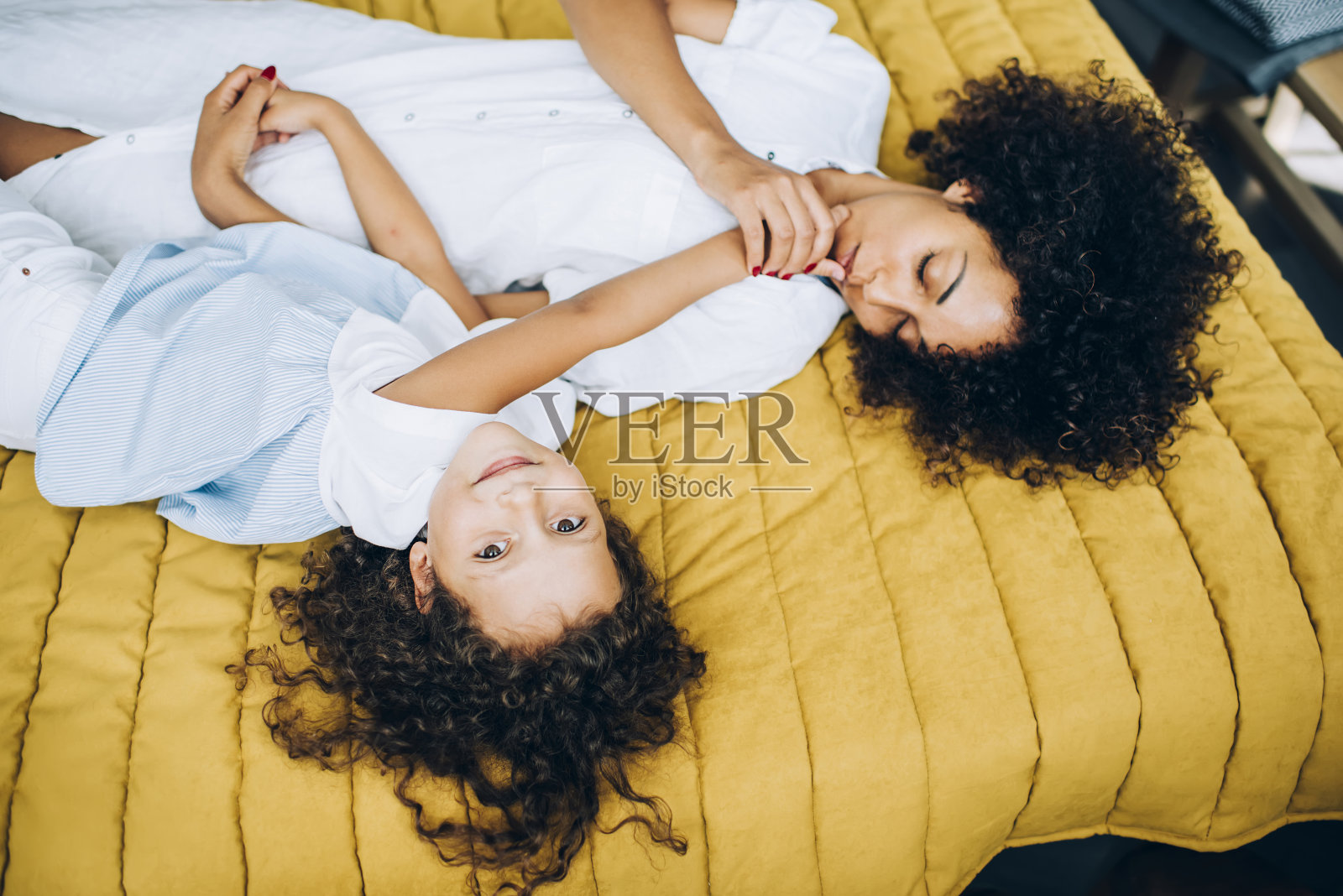 民族女士在床上亲吻女儿的手指照片摄影图片